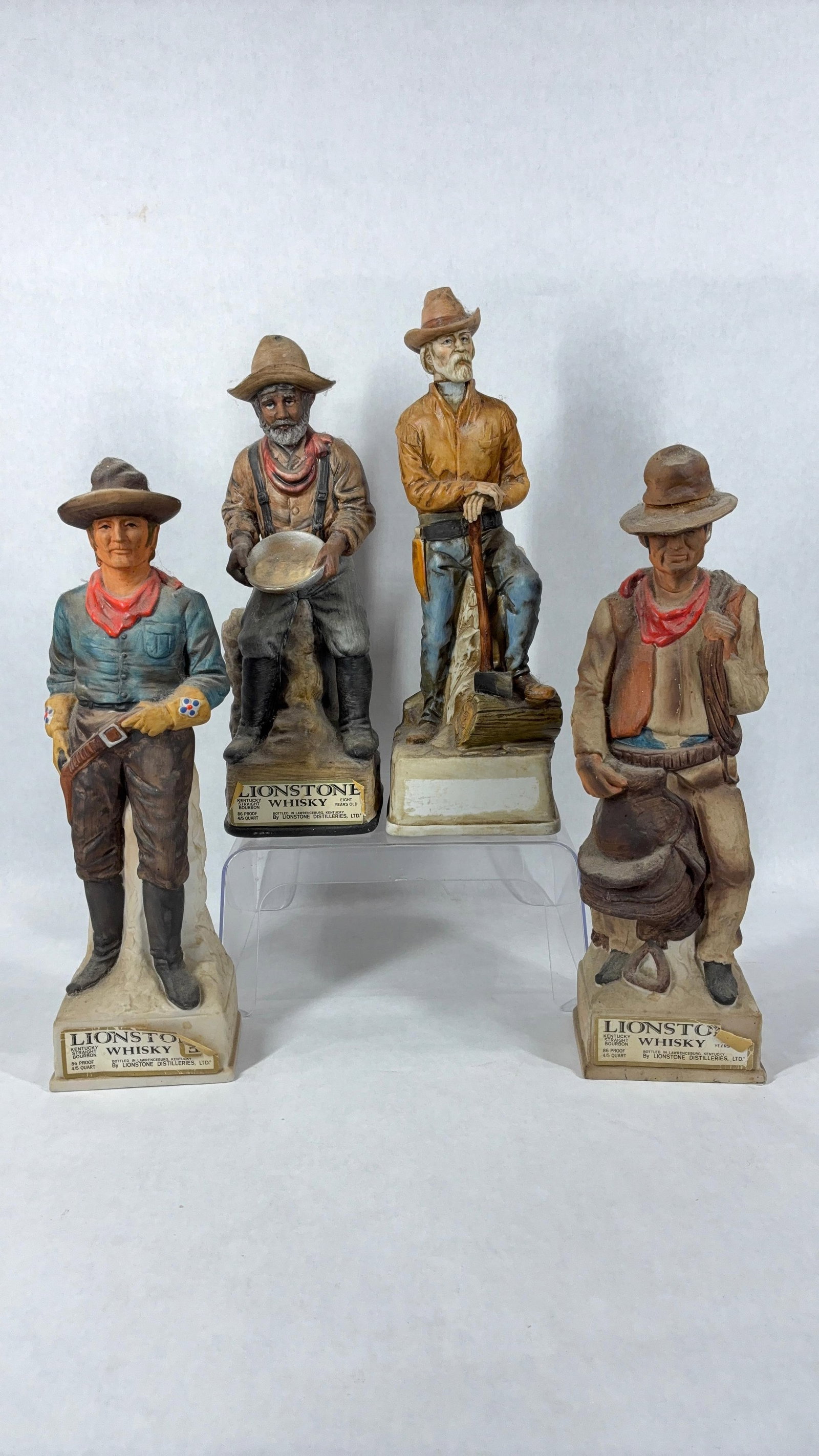 Lionstone Old West Series Whiskey Decanter Bottles: Includes Cowboy Cavalry Scout, Belly Robber, Gold Panner, and The Woodhawk. Approx 14 inches tall.