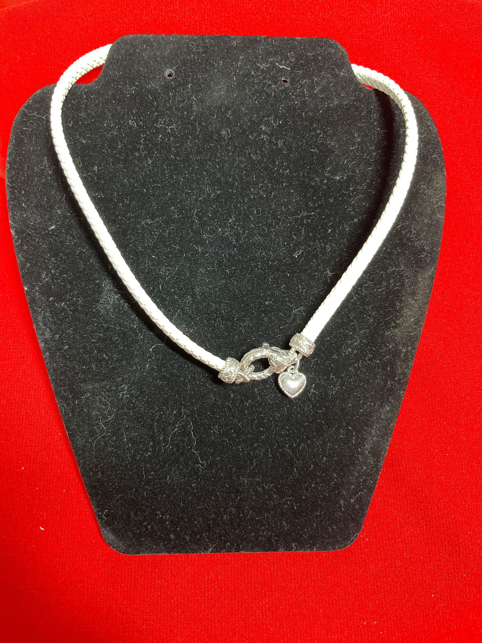 Judith Ripka Rose Sterling Cord & CZ Stone Necklace: White leather braided cord, and heart shaped pendant with CZ stones. Approx 17.5 inches