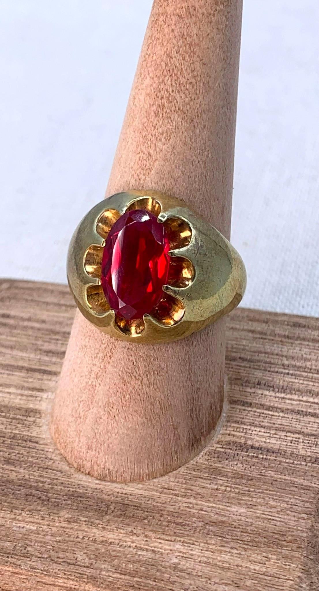 Glitzy Mid Century Men's Large Carat Created Ruby Ring: Burnished gilded brass framework, 13x8mm created Ruby, 10.25 size, 10.8 gram weight.