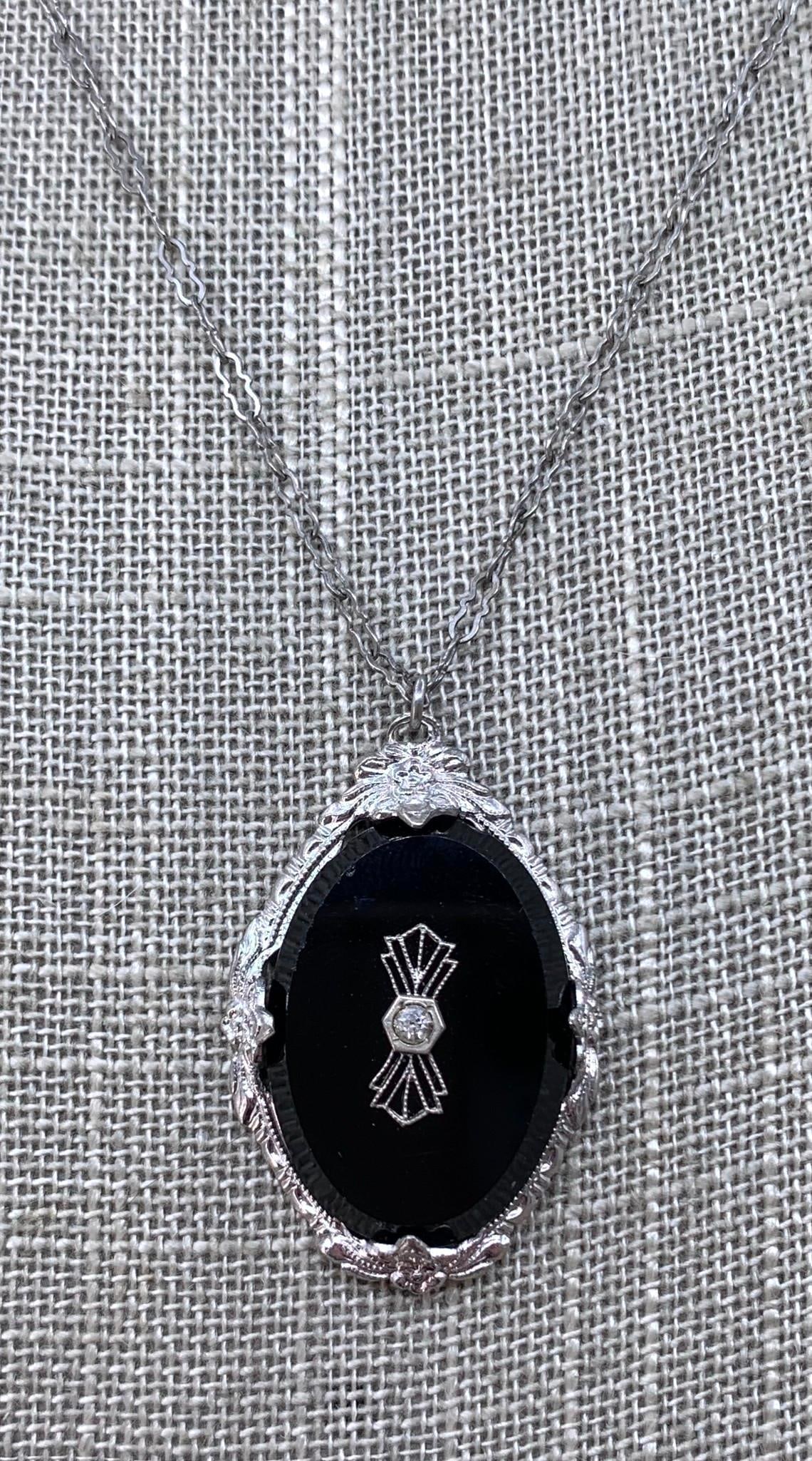 Sublime 1920s Art Deco Black Glass Rhinestone Pendant: Fancy openwork 16" circumference chain, embossed silver metal framework, oval faceted jet black glass with filigree framed rhinestone inset, 1 3/8" x 7/8" pendant.