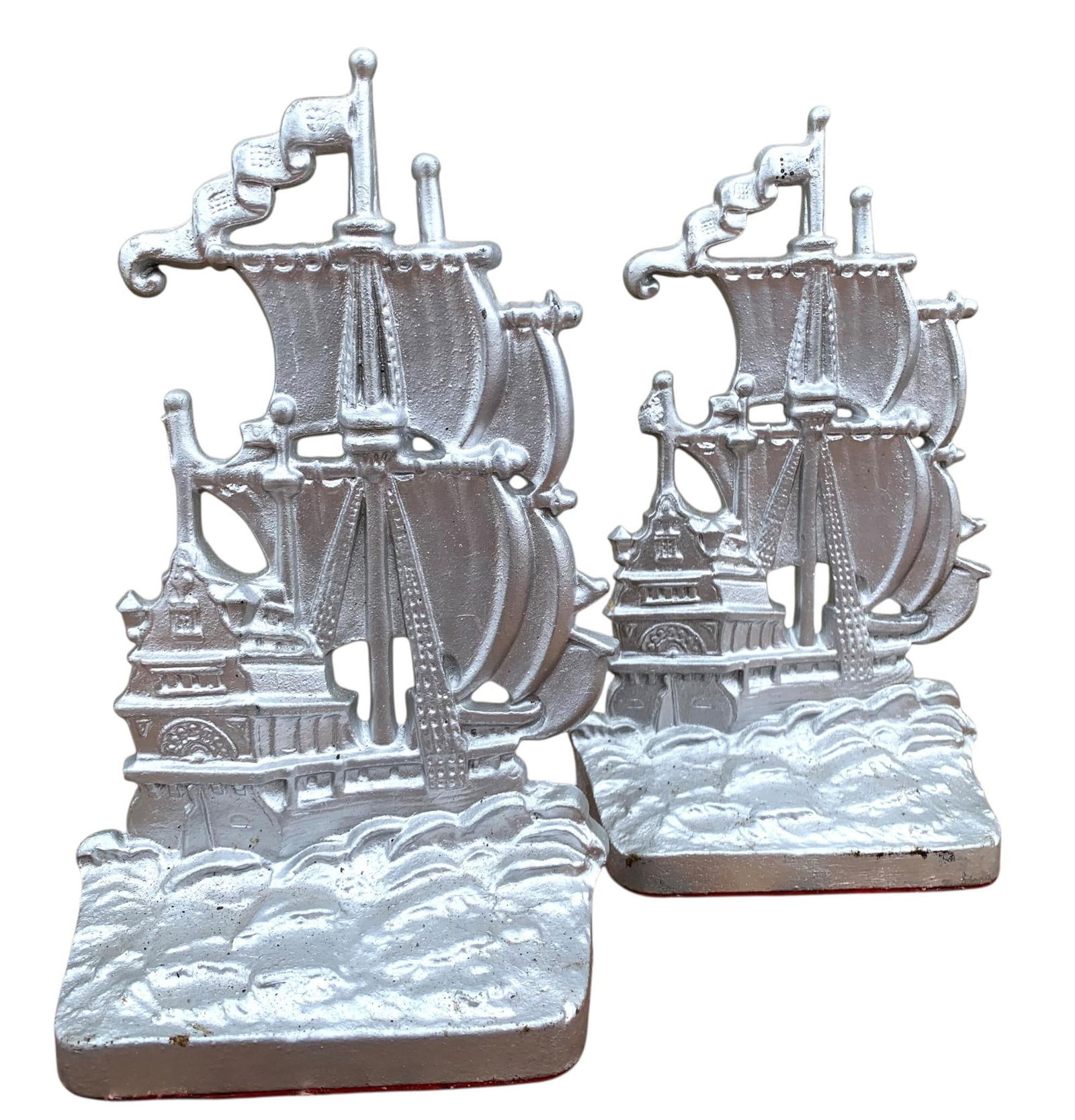 Pair Antique 1920s Cast Iron Nautical Galleon Sailing Pirate Ship High Relief Seville Bookends: 9"tall, hefty in weight with a silvered enamel finish, manufacturing marks on the rear, felt base liner.