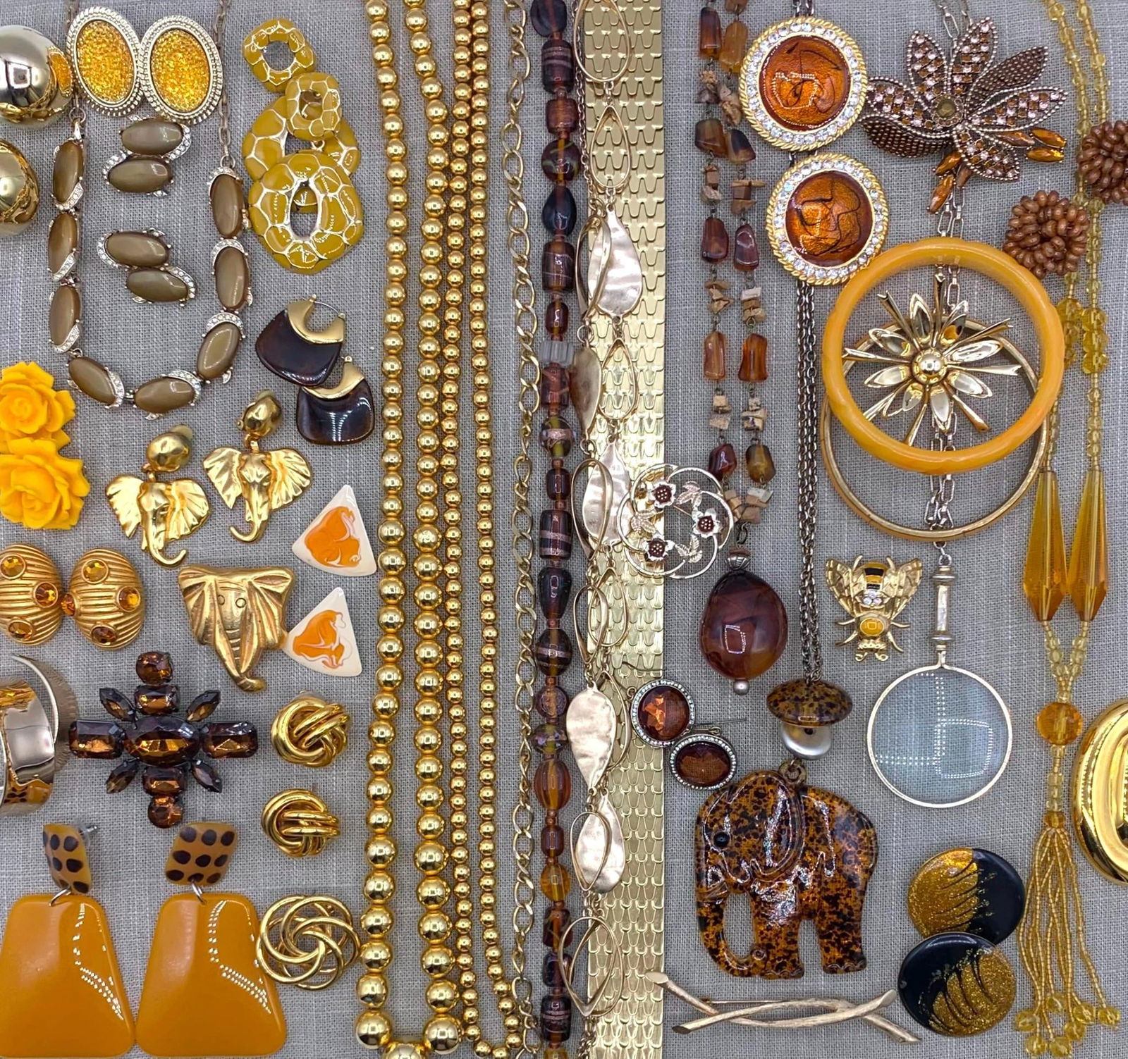 55 pc 1920's to 90's Vintage Faux Amber Costume Jewelry Collection in Velveteen Lined Book Box: Flapper era goldenrod glass tassel necklace, faux amber Elephant pendant, golden brooch and oversize clip Elephant earrings, glittering rhinestones, glowing enamel, huge gold dome clip earrings and ov
