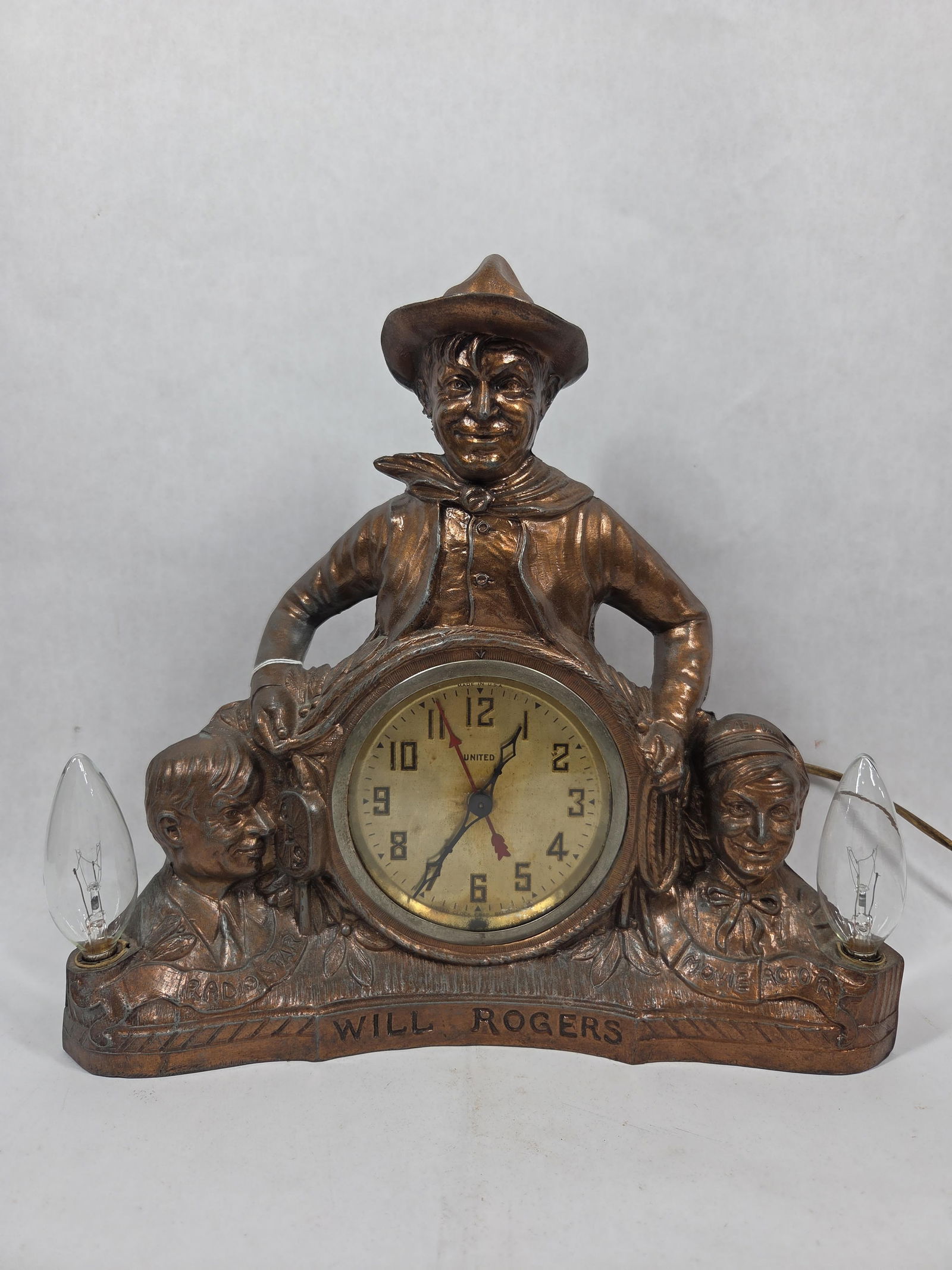 United Clock Co Will Rogers Novelty Clock: Painted gilt spelter featuring three figures, clock, and lights. Clock is not running but lights work as they should. 13x12.5