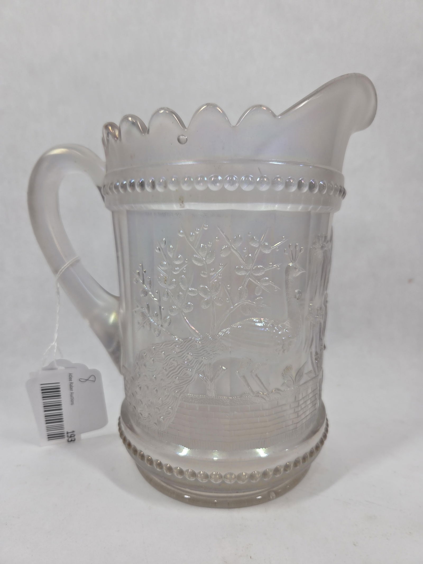 Northwood Peacock at the Fountain White Carnival Glass Pitcher: A small repair shows to bottom edge. 8 inches tall