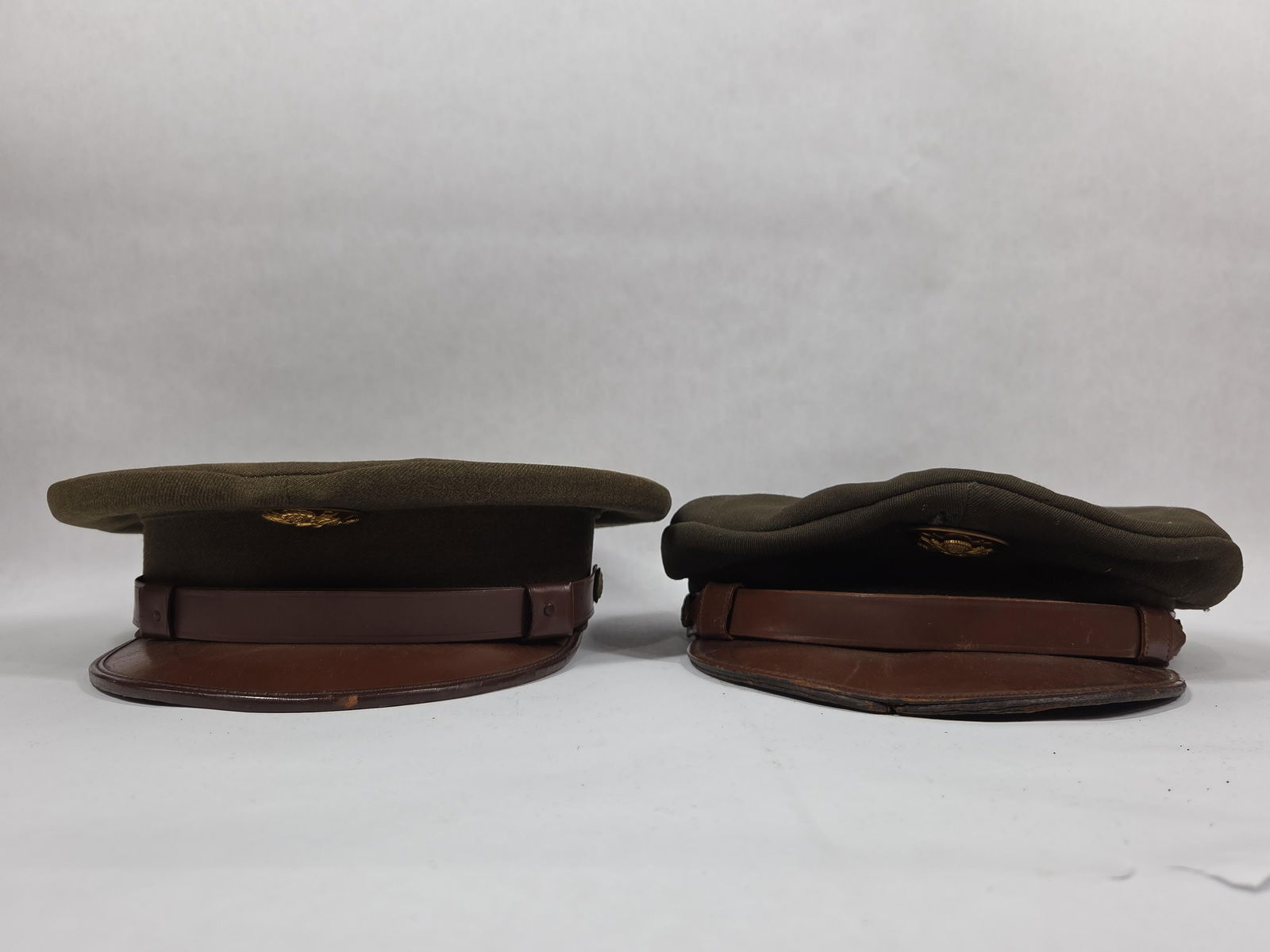 United States Army Dress Caps: 2 wool caps both showing Brass US Army badges. Overall good condition