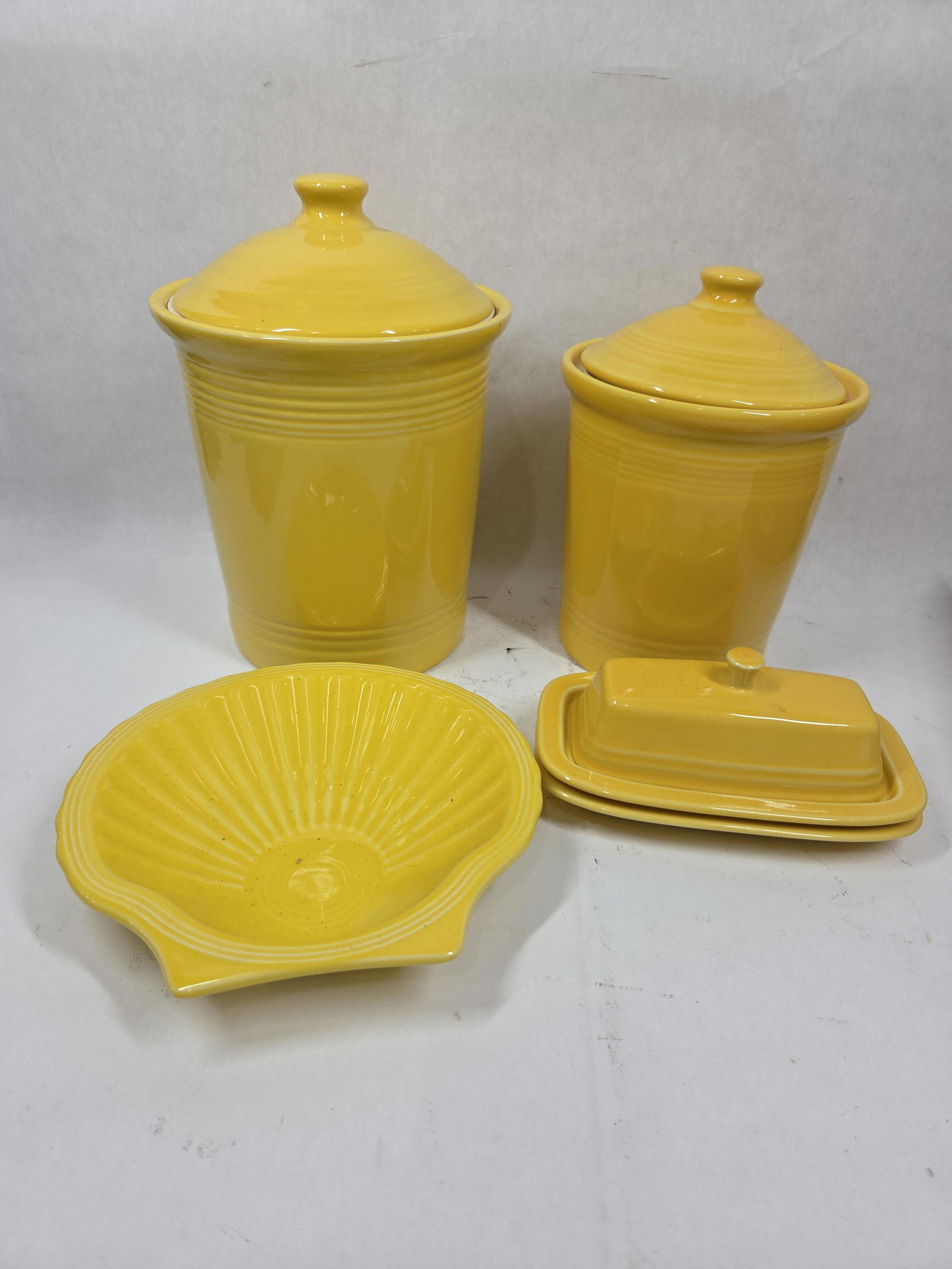 Sunflower Yellow Fiesta Cannisters, Butterdish, and Shell Platter: 5 pieces all in good condition. Canisters are 7 and 8 inches tall
