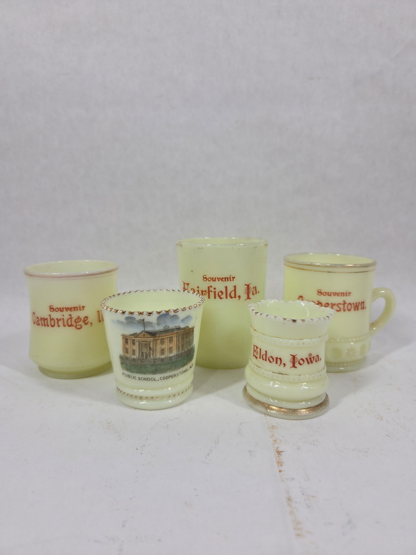 Uranium Glass Souvenir Mugs and Holders: Fairfield Ia, Cambridge Ill, Eldon Iowa, Cooperstown, and Public School Cooperstown ND. All glow brightly under UV light. No large chips or cracks are found