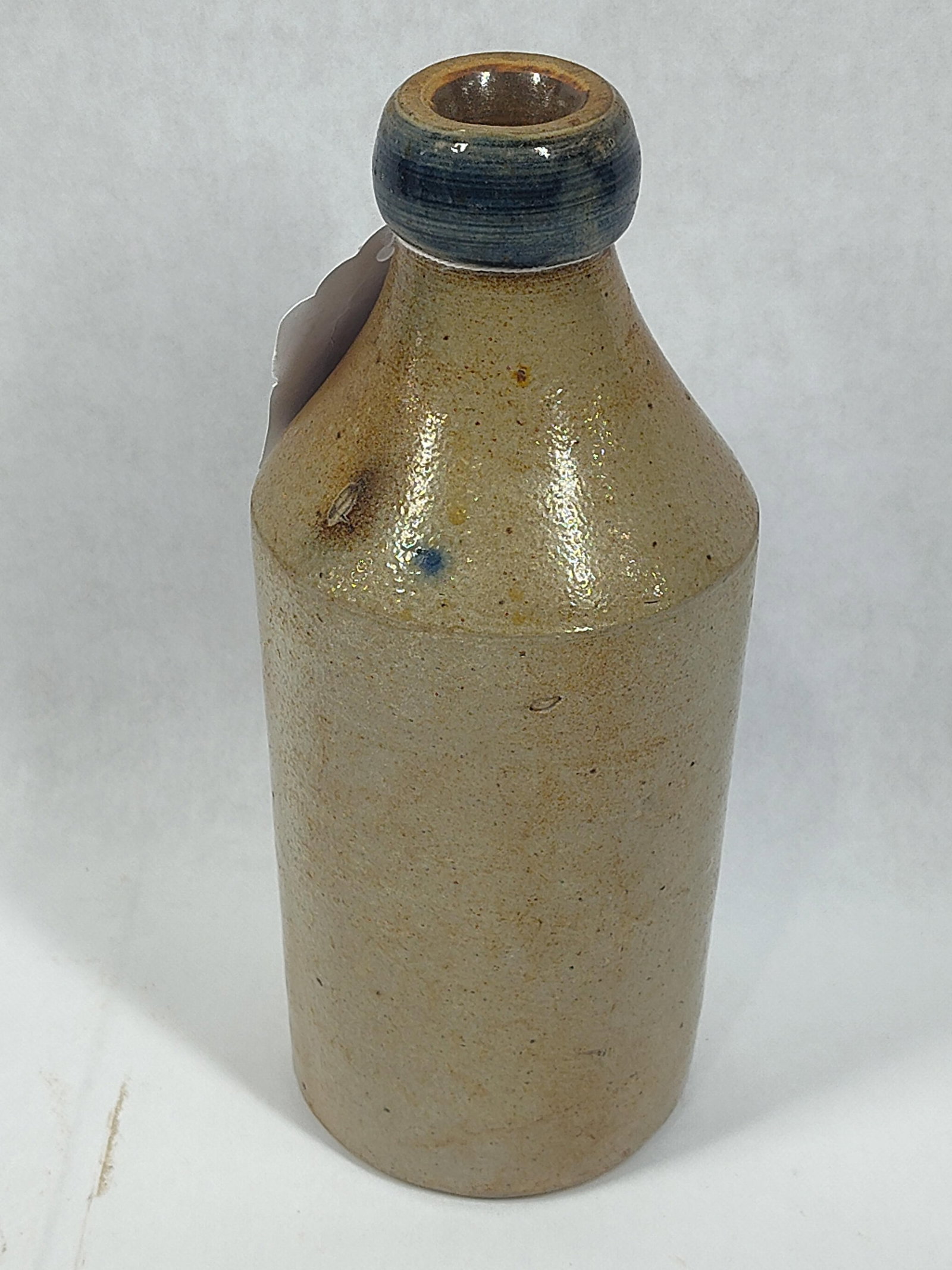 D. Gooding Stoneware Bottle: Traces of blue glaze along top. One chip shows to the bottom, no cracks. 9 inches tall.
