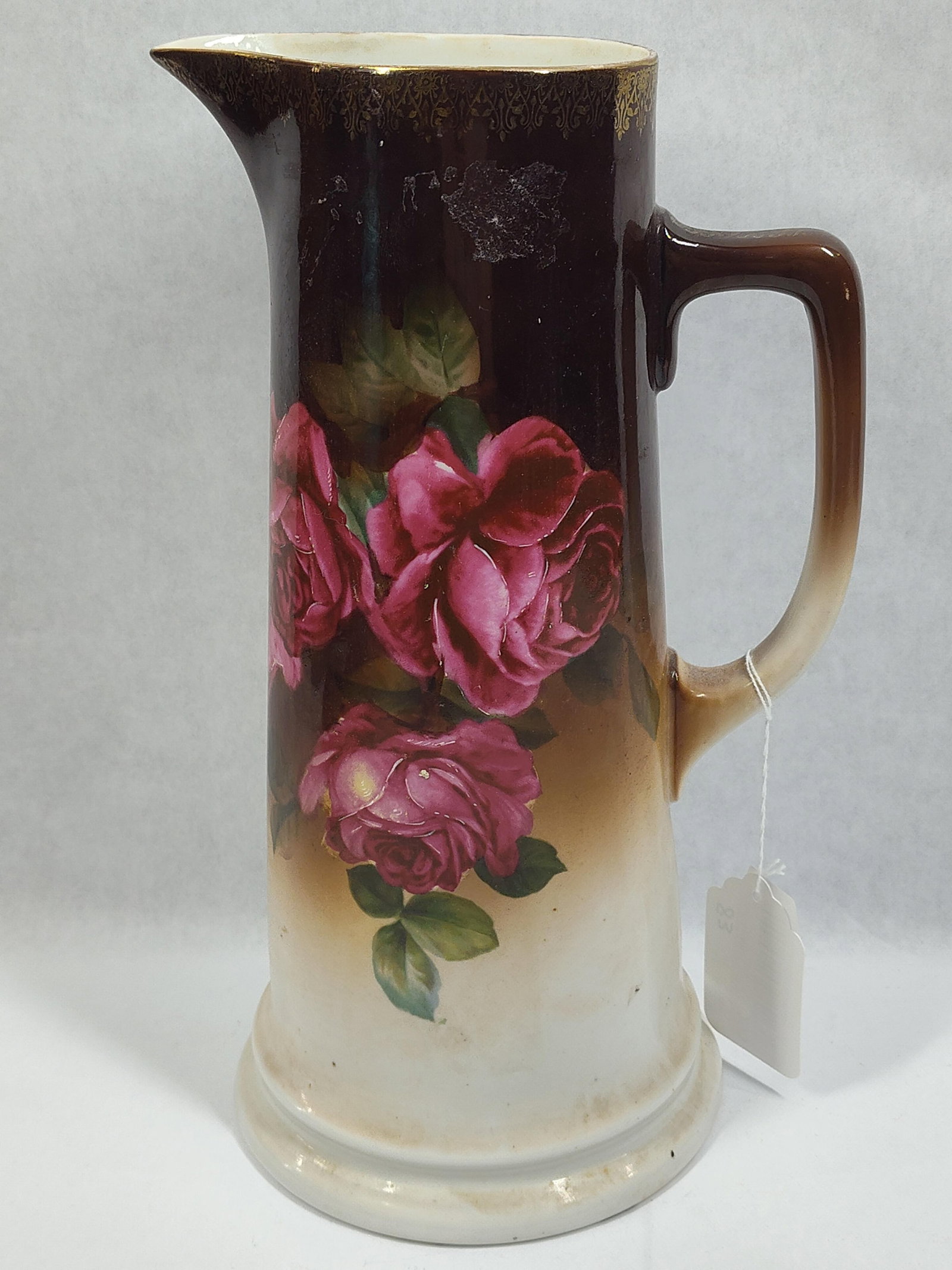 PT John German Pitcher: Late 1880s made featuring a rose design and brown to white tones. Gold trim show along handle and to rim. No chips or cracks. 13 inches tall