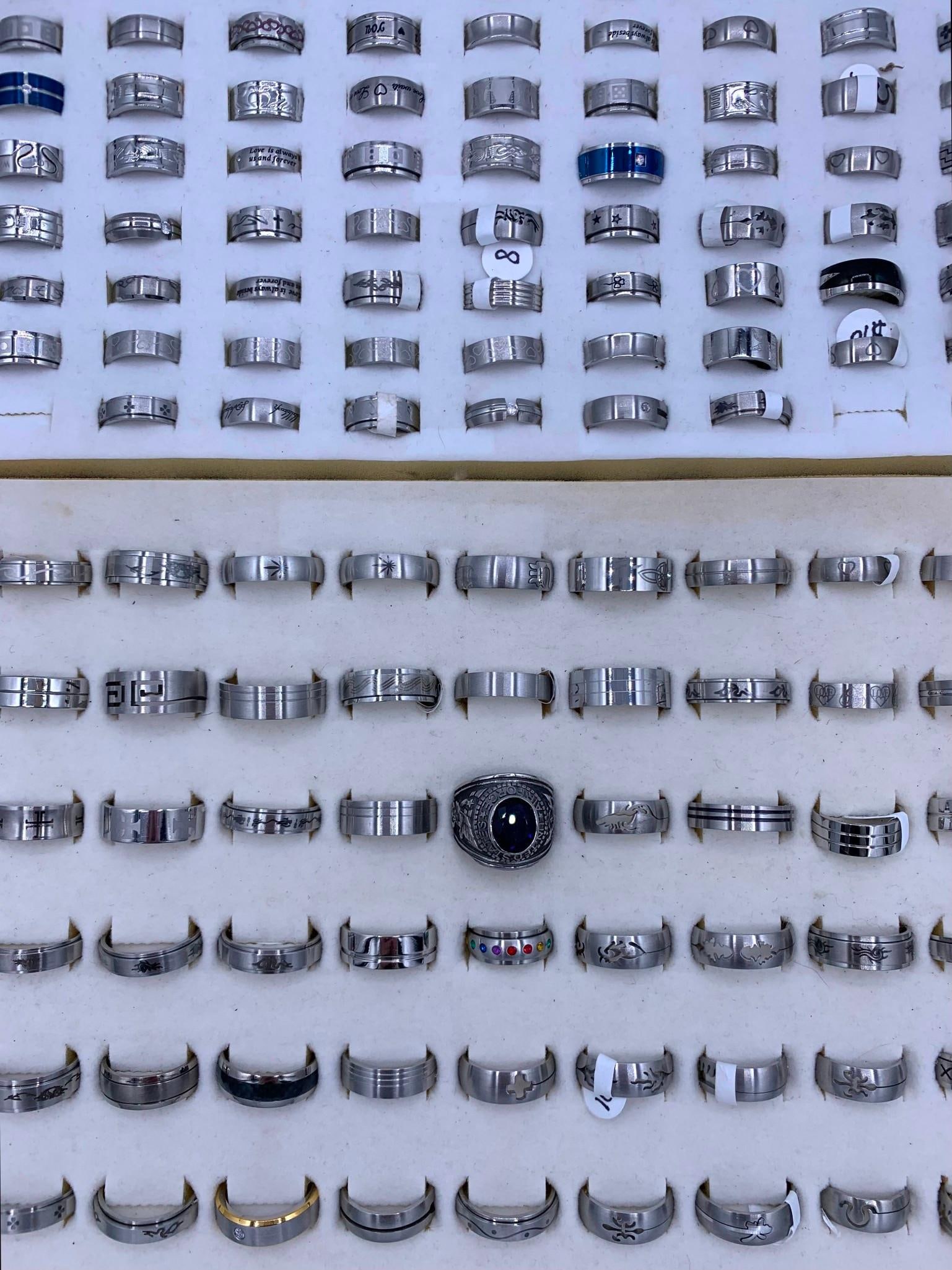 202 pc NOS Fashion Jewelry Rings: Unworn with size and price tags on most, size 5 to 13, embossed, etched, puzzle, spinner, rhinestone accents, large US Military style ring and more! 2 vintage velveteen ring storage inserts are includ