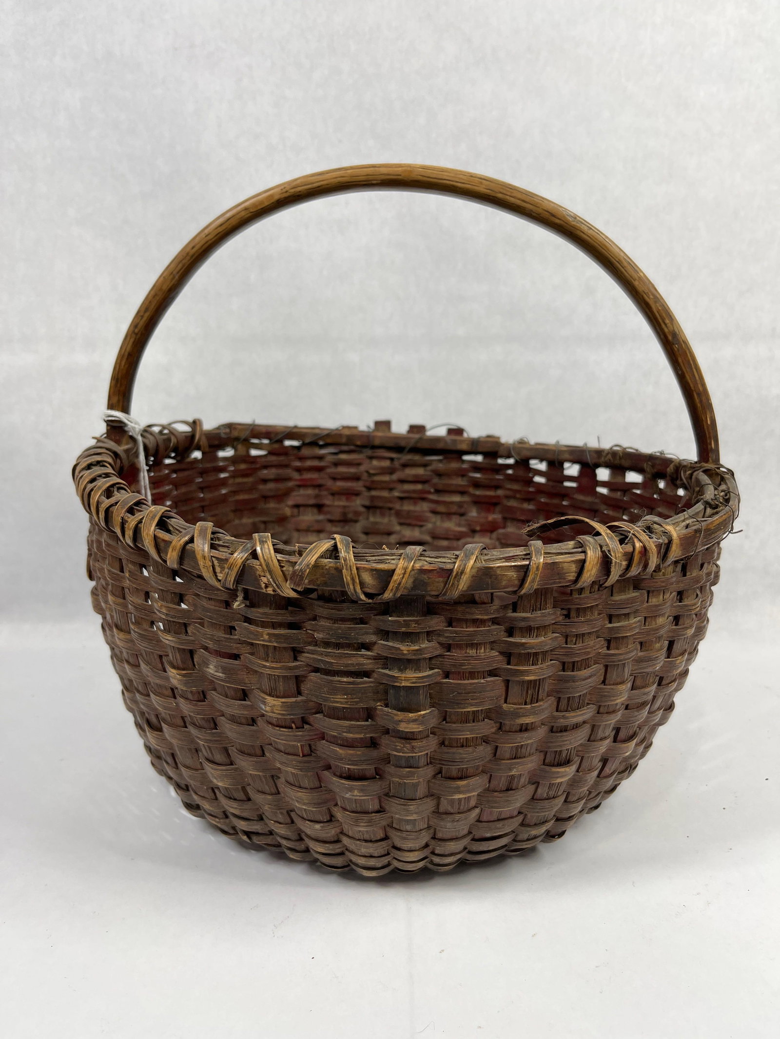 Wonderful Red Stained Market Basket: Several loose banding along edge with added wiring for stability, but otherwise a tight weave. An early red stain to this nice early piece. 14 inch diameter