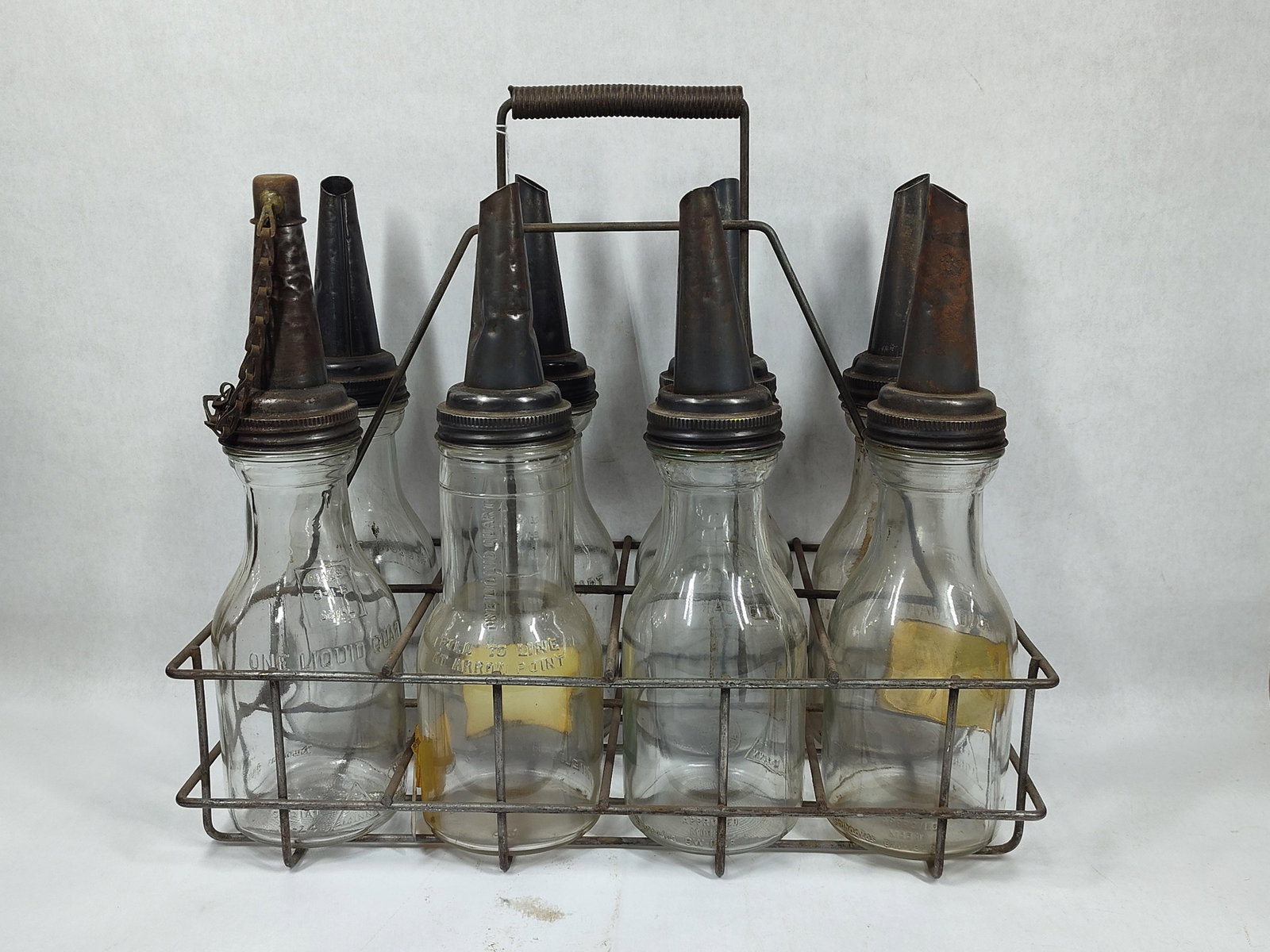 8-Glass Oil bottles with carrier: 7 are identical, 1 is a Shields, Harper & Co.