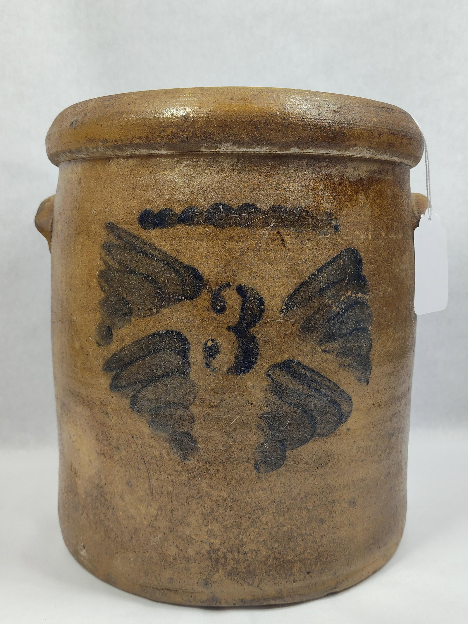 Decorated 3-gal Stoneware Jar: With a chip on rim, handle and base, also shows a 3in hairline from rim close to left handle and a few other hairlines that are hardly noticeable. 12in tall.
