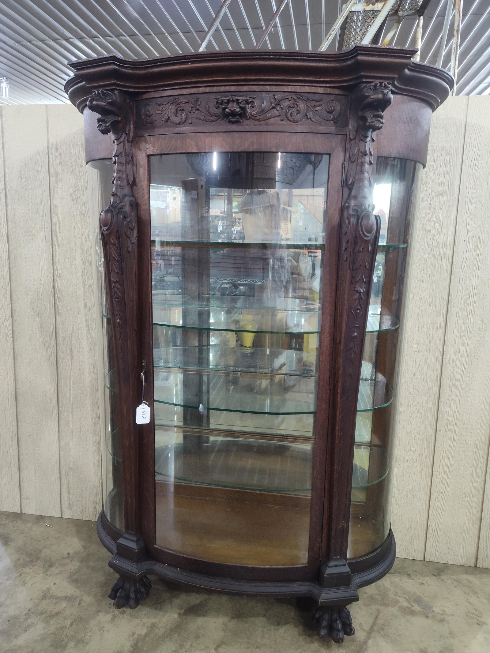 Outstanding Oak Curved Glass China Cabinet (Probably R.J. Horner): Beautiful early carved oak cabinet with Griffins/Lion Heads and claw feet on casters!! Features mirrored back and 4 adjustable glass interior shelves. Original finish and in great original
