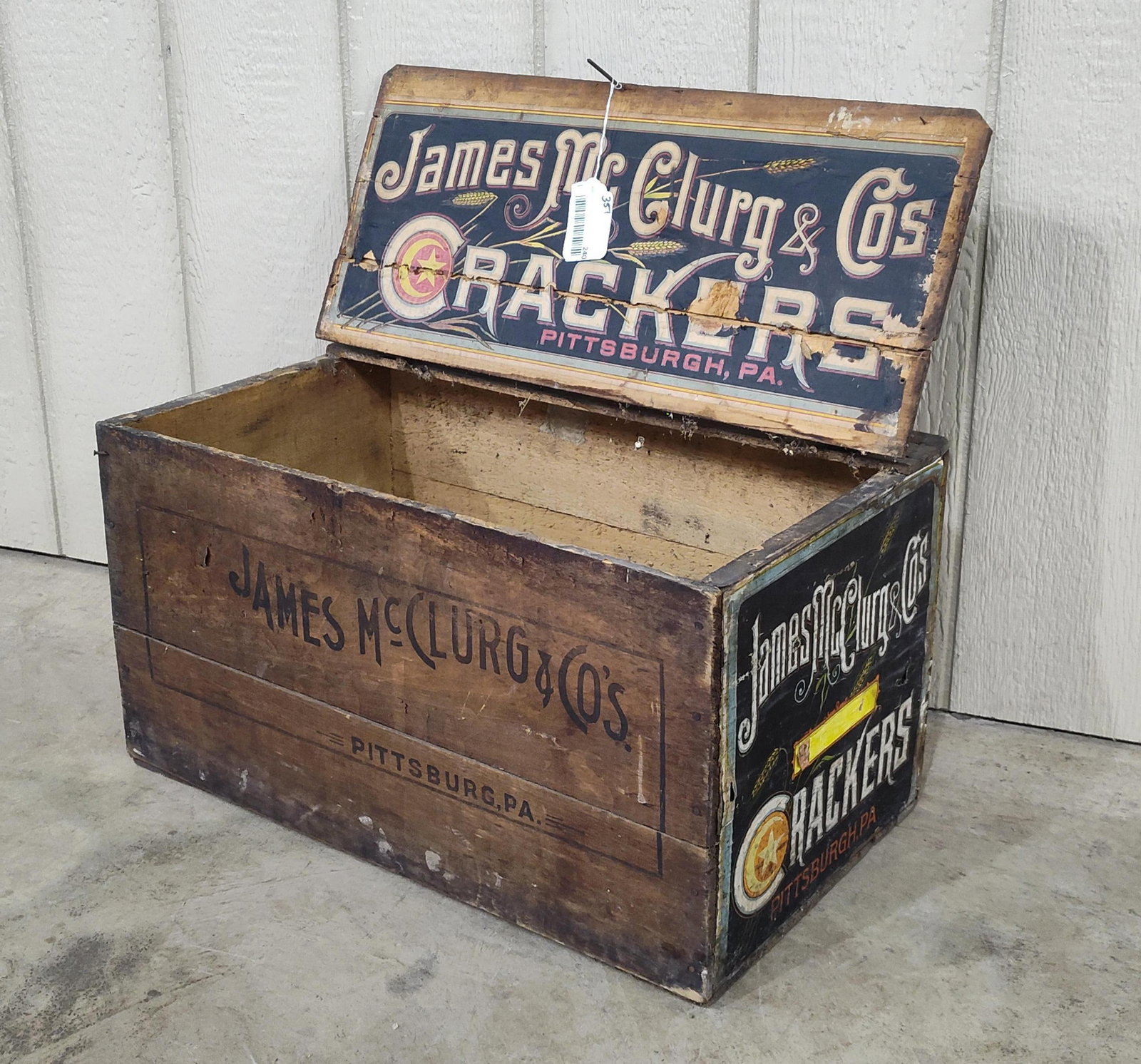 James McClurg & Co Crackers shipping box: With original label on one end and interior lid. Stenciled graphics on both sides. Hinged lid. 24in long 13in wide 13in tall.