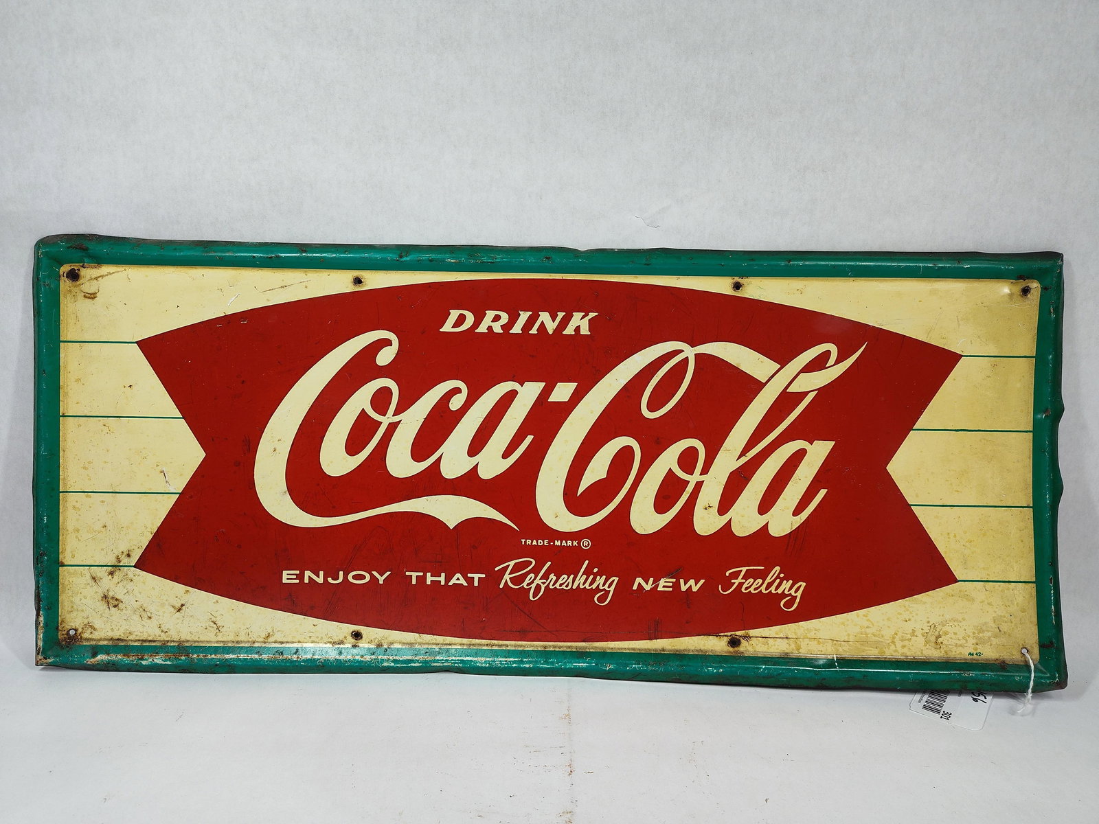 SST Coca-Cola Fishtail self-framed sign: 1-sided painted metal self-framed sign with some scuffing and scratches but presents well! Marked A-M 42. 12in X 28in.