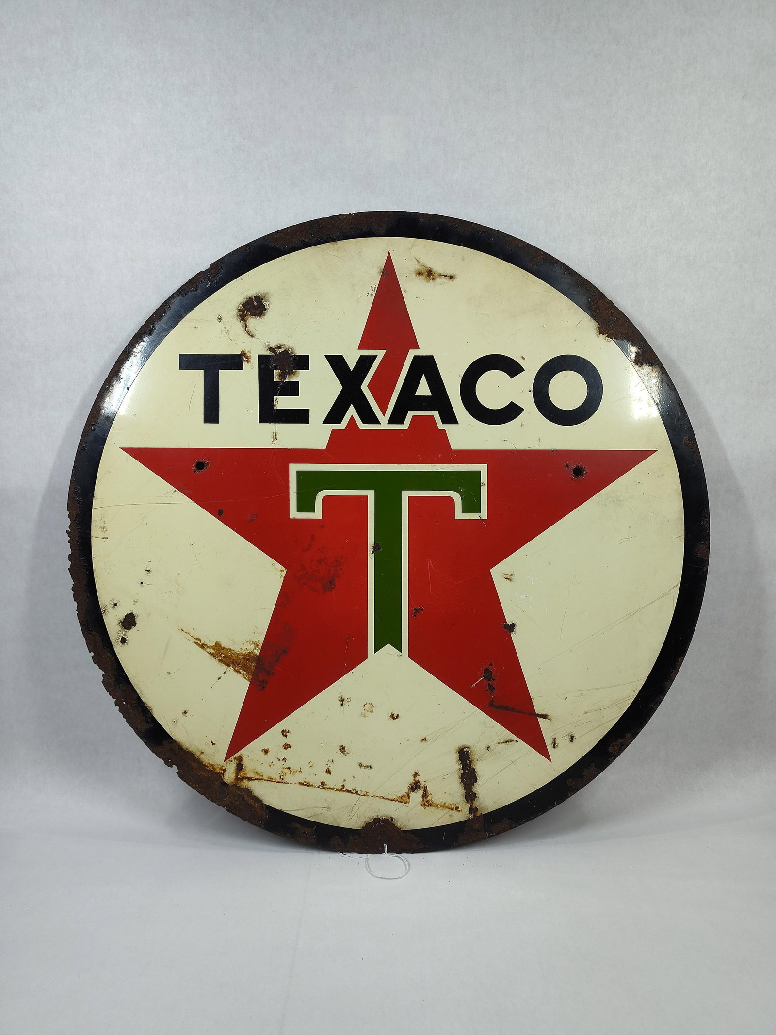 SST Texaco "White T" 24in sign: 1-sided painted metal sign with areas of heavy corrosion along edges and some in field but still displays well!! 24in diameter.