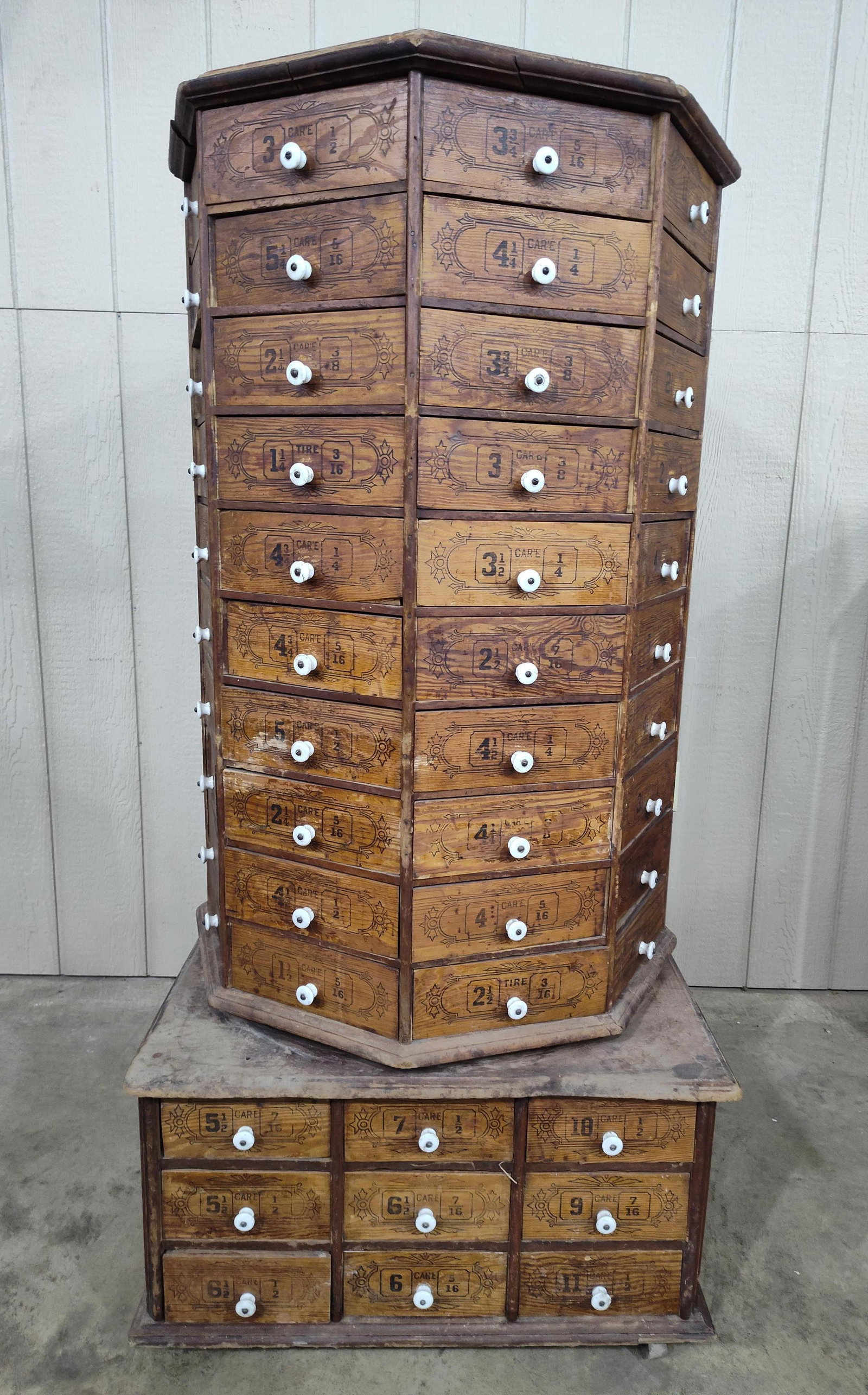 Outstanding Octagonal 98drw Rotating Hardware Cabinet: Base with 9 rectangle drawers on casters with rotating tower features 80 pie shaped drawers, all with porcelain pulls. Shows areas of wear to original surface but overall is in good solid condition