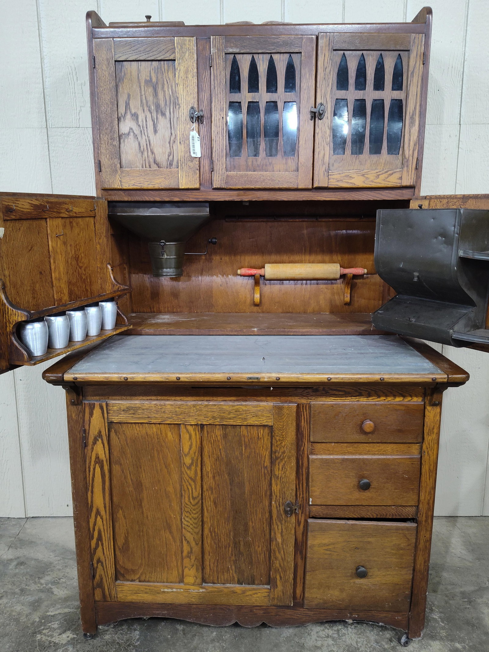 Great early Oak 2pc Hoosier Style Cabinet: Contains tin flour sifter with hinged lid on top to refill and tin container mounted to interior door. Also comes with 5 spice containers. Shows cracks to backer, overall is a nice piece! 40in wide