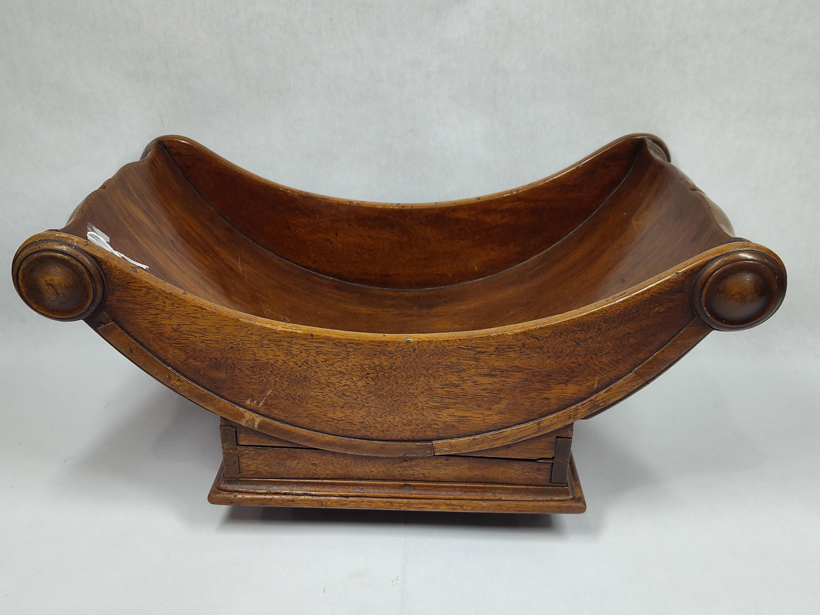 Antique Regency 19th cent Mahogany Cheese Cradle: Unusual Cheese cradle/coaster with swiveling top and sets on casters. Base with dovetailed corners. 17in long 10in wide 8in tall at the ends.