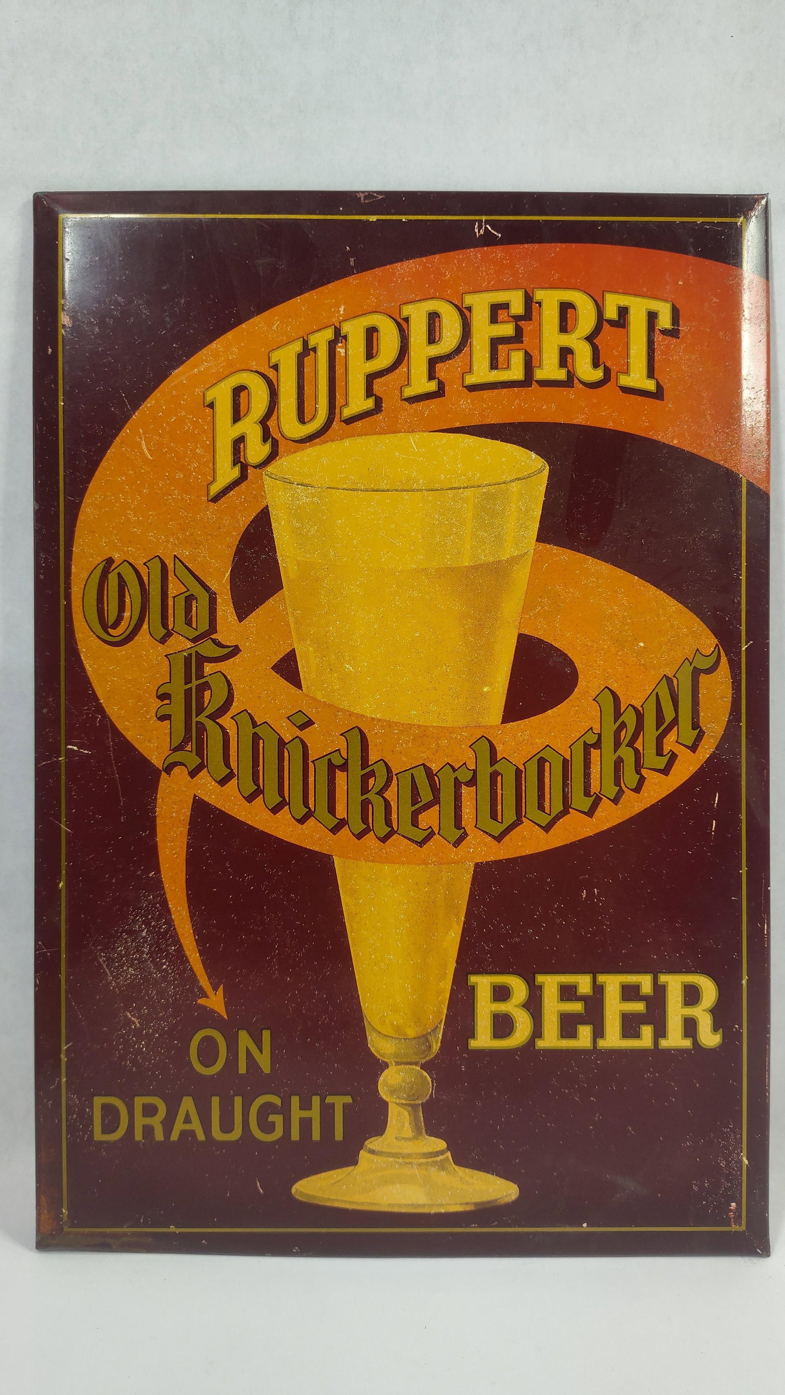 TOC Ruppert Old Knickerbocker Beer easelback sign: 1-sided painted tin over cardboard sign with easelback. Shows spotting. 9.25in x 13.25in.