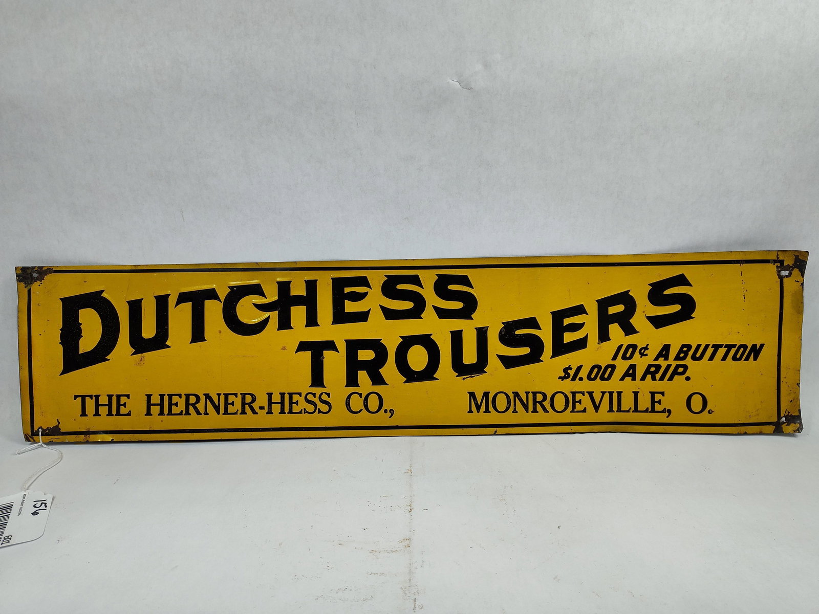 SST Dutchess Trousers embossed sign: 1-sided painted tin embossed sign with a few wrinkles and some wear at corners but overall is decent. 6.5in x 28.25in.