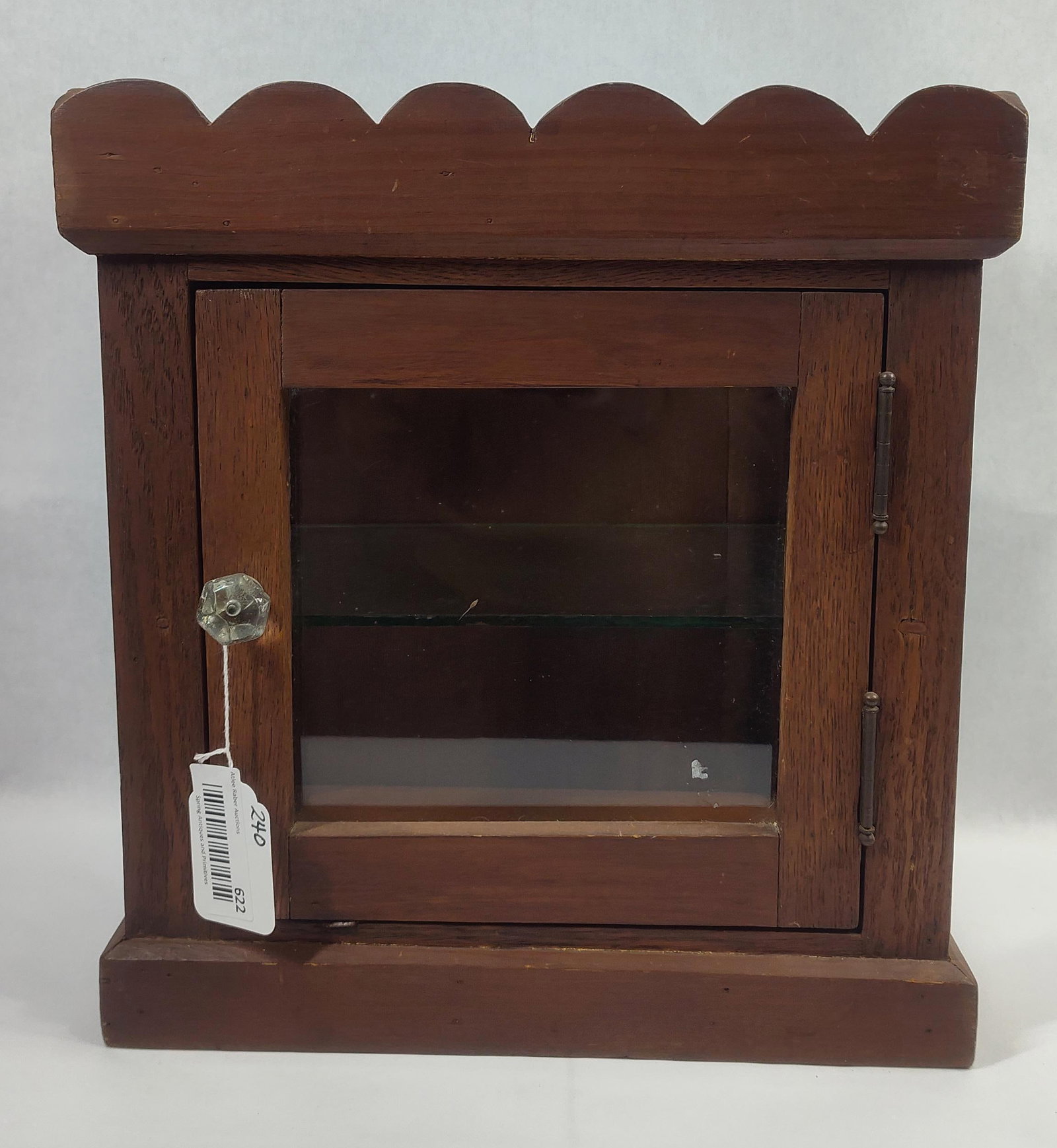 Small Wooden Medicine Cabinet with Scalloped Top: With glass panels in sides, door and one glass interior shelf. Veneer on back shows some buckling. 15in wide 9.5in deep 16in tall.