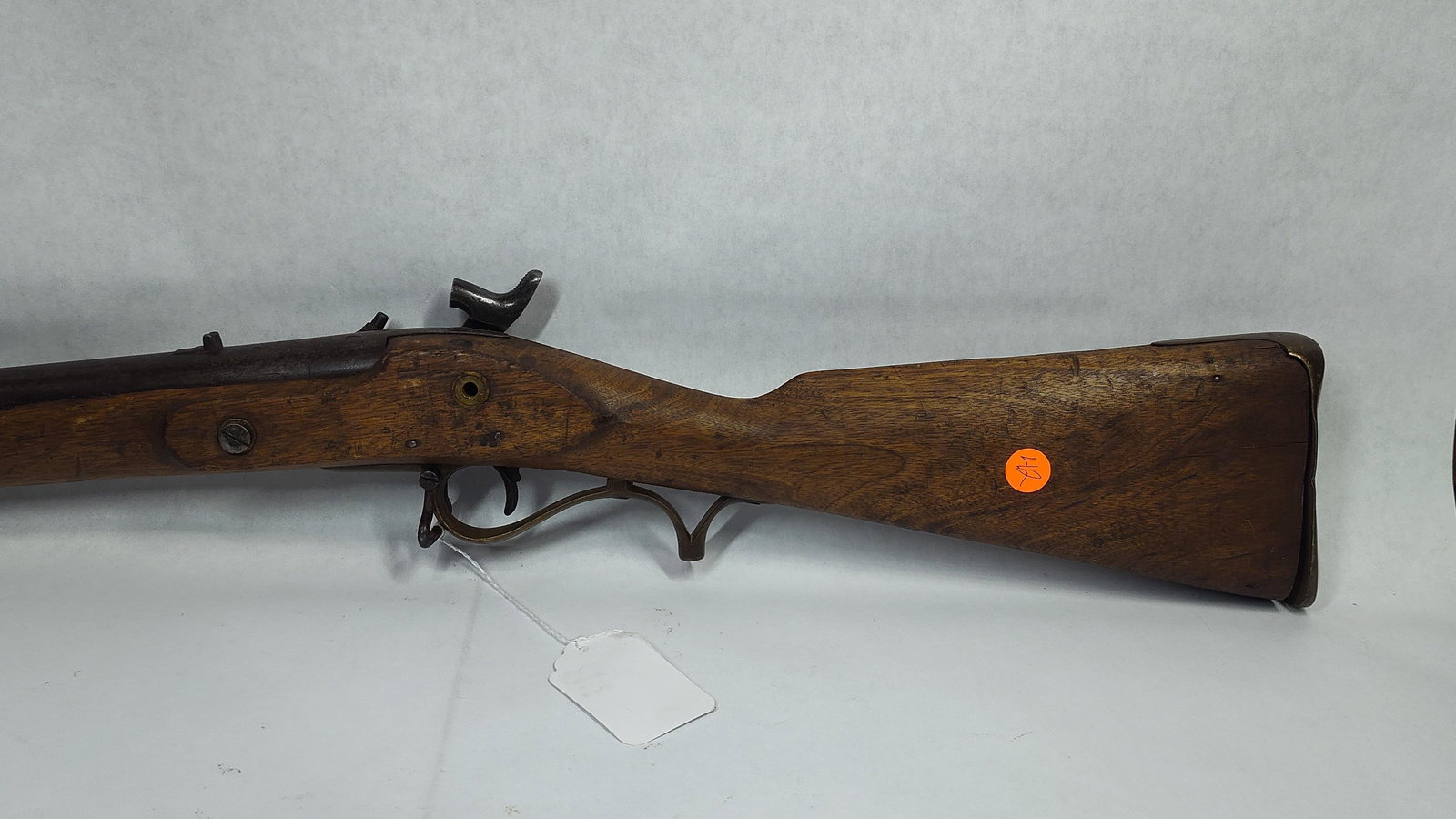 Black Powder Percussion Rifle Wall Hanger: A few small marks from the maker can be found on the trigger guard and barrel. Brass hardware and an oak stock. 56 inches long. Several numbers are found by handle. Butt plate is a little loose. 