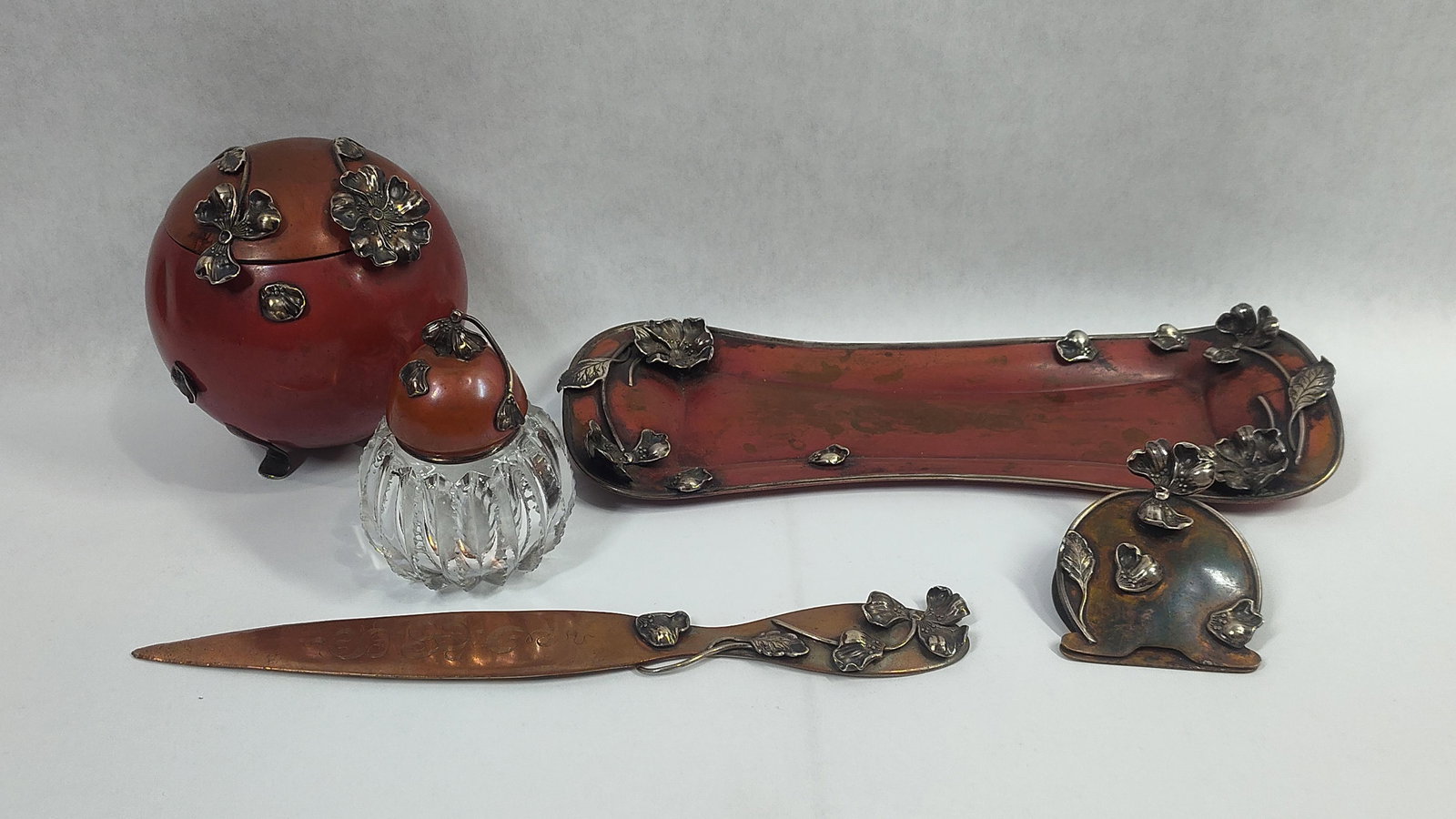 La Pierre Sterling & Copper Desk Set: Including 5 pieces each with red enameled foundation, copper, and sterling floral arrangements. One piece is Inscribed and dated 1905. 