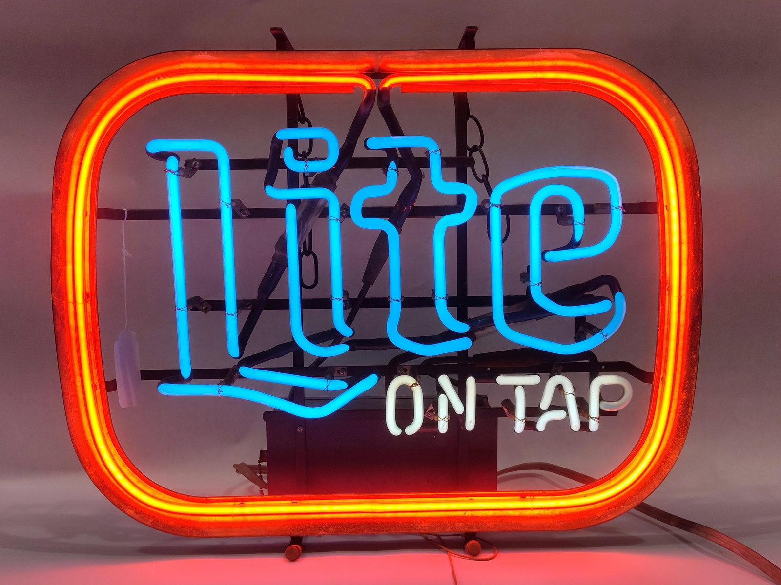 Miller Lite On Tap Neon Advertising Sign Dated 1977: Thisneon advertising sign was produced for the Miller Brewing Company in 1977. The sign features the Miller Lite logo rendered in blue glass neon tubing positioned above the phrase ON TAP in white neo