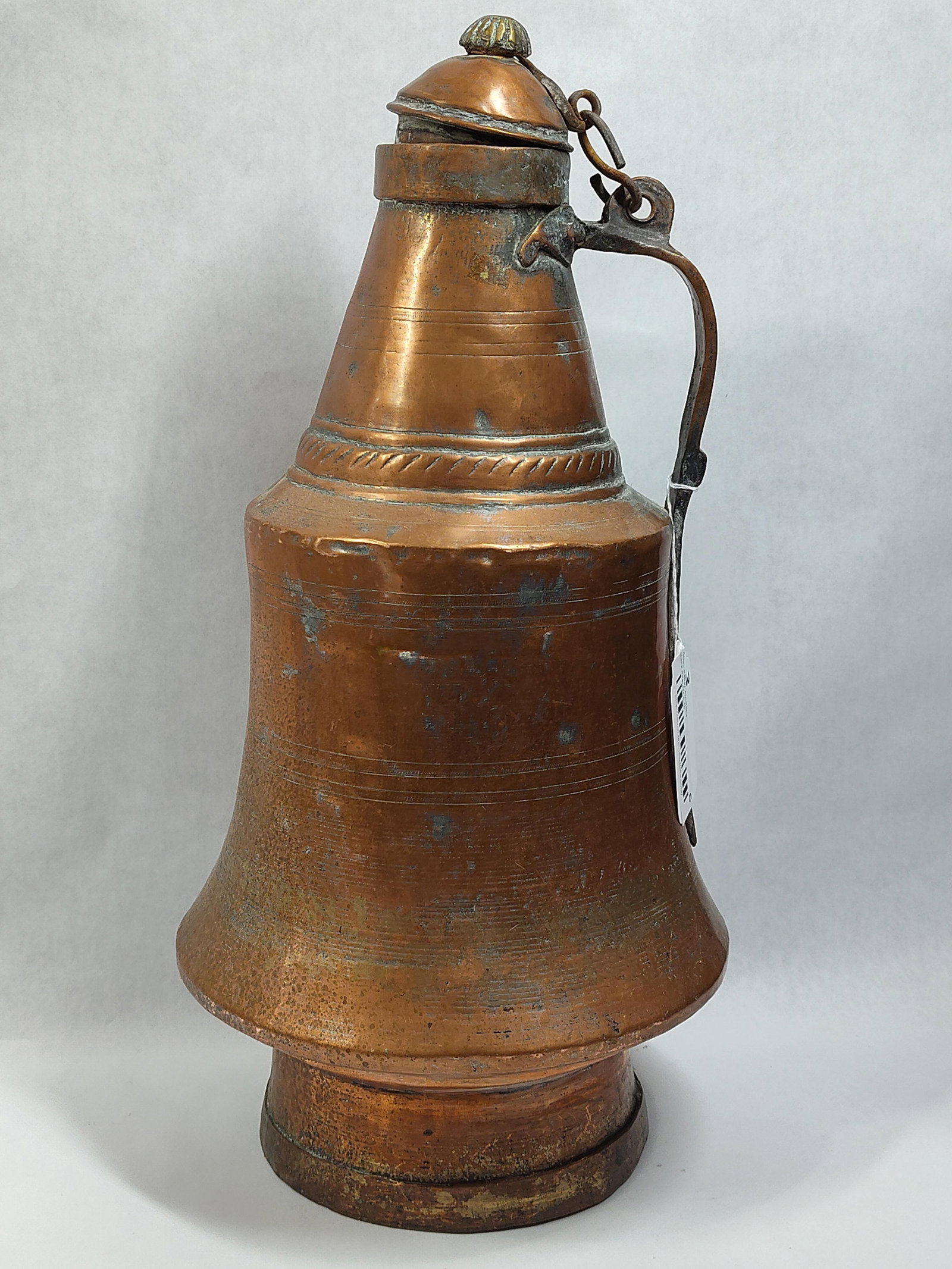 Antique Turkish Hand Hammered Copper Lidded Pitcher with Tinned Interior: This large antique copper pitcher is crafted in the traditional Ottoman or Turkish style, featuring a hand hammered construction. The vessel is designed with a tapered conical neck transitioning into 