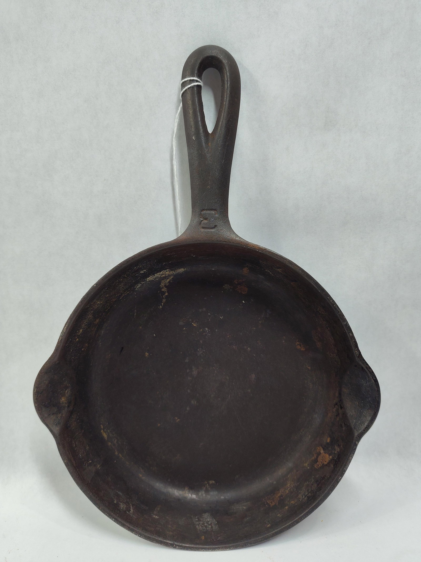 Griswold No. 3 Cast Iron Skillet Small Logo Pattern 704: This is a Griswold No. 3 cast iron skillet, manufactured in Erie, Pennsylvania. The object is cast from iron and features the Griswold small logo centered on the underside, consisting of a cross withi