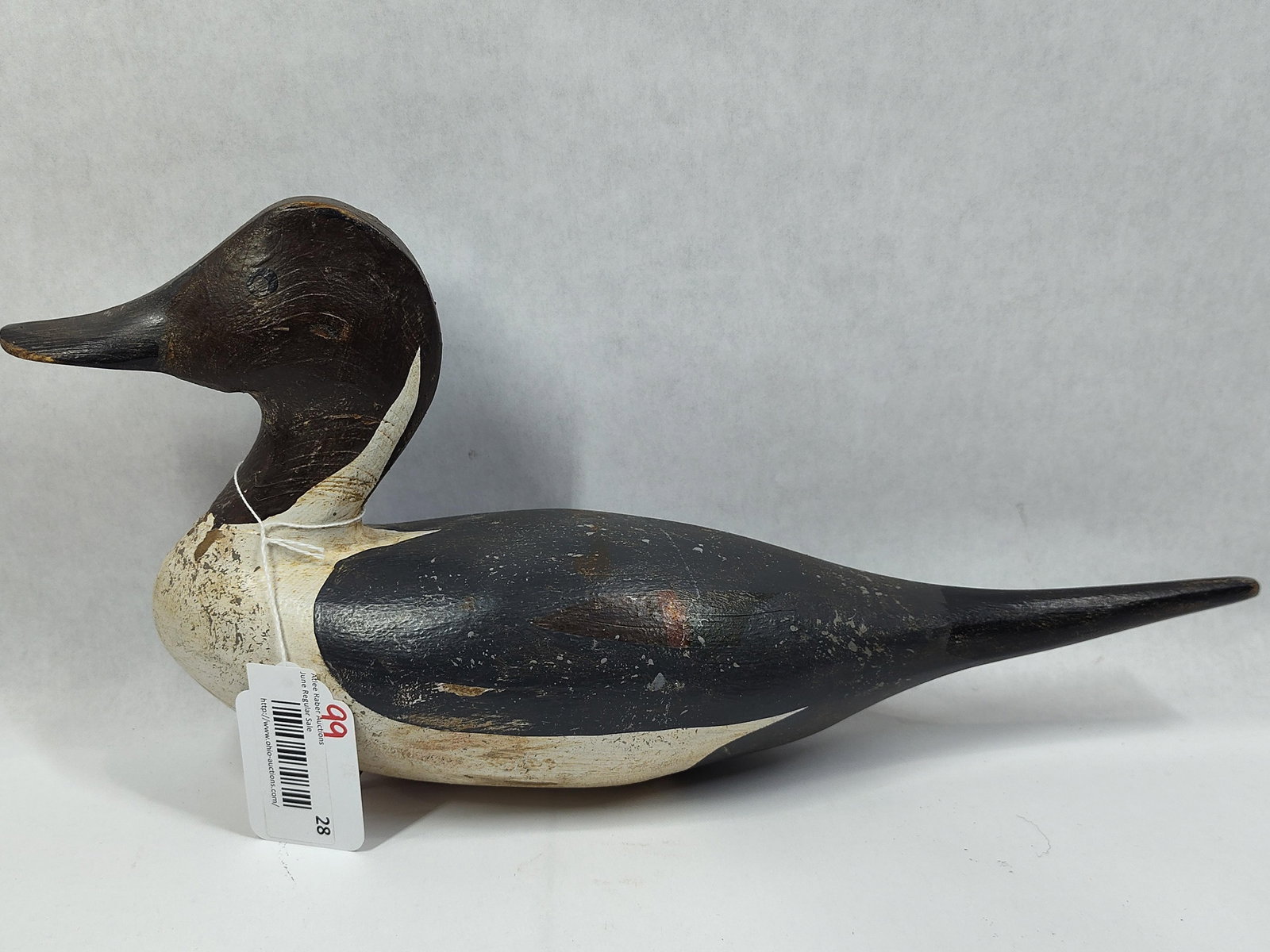 Hand-Carved Wooden Drake Merganser Working Duck Decoy: This hand-carved wooden working duck decoy is modeled as a drake merganser, featuring a notably elongated and tapered tail consistent with folk-art interpretations of the species. The decoy is