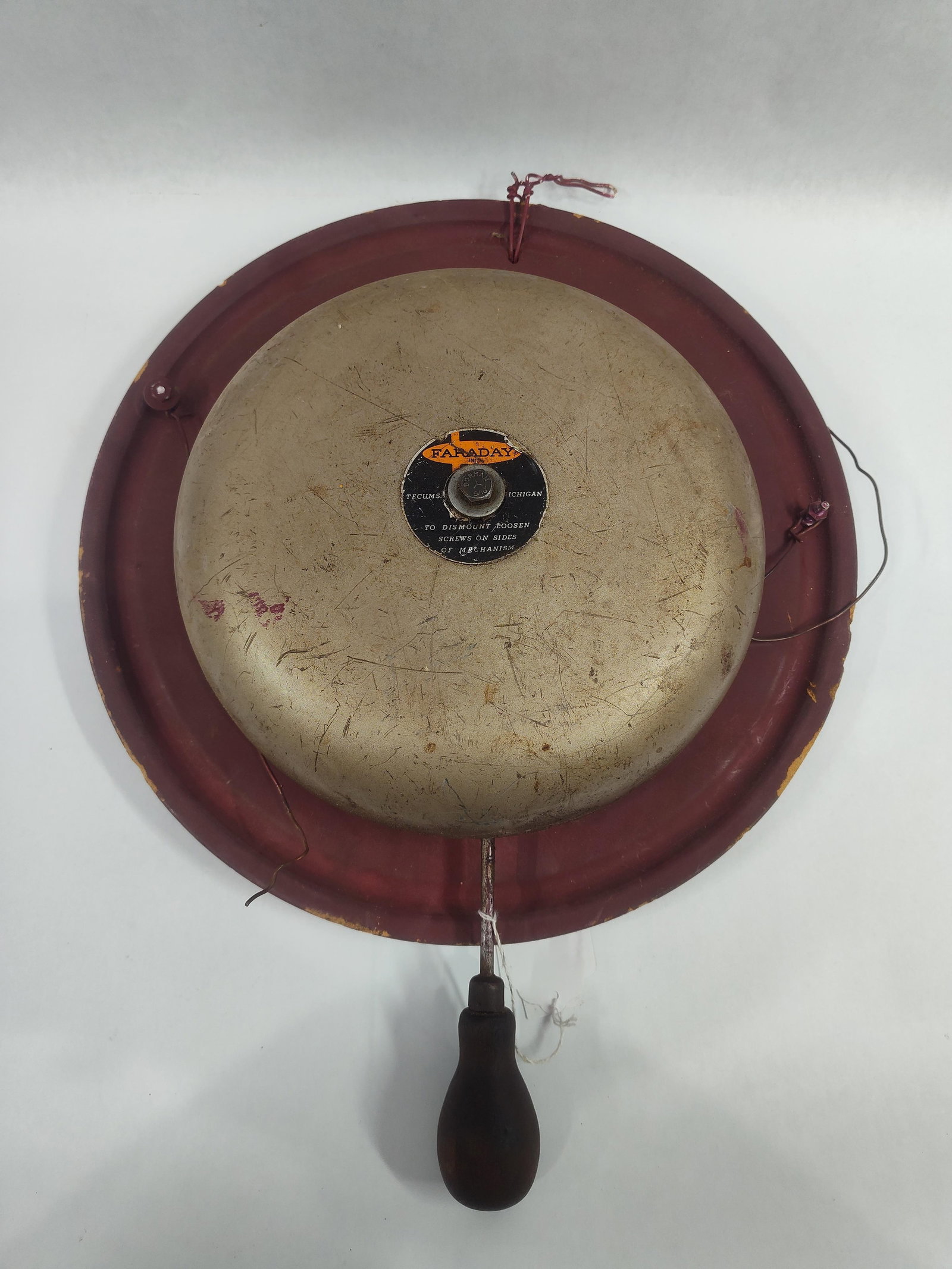 Faraday Inc. Industrial Electric Alarm Bell: Aindustrial electric alarm bell manufactured by Faraday Inc. of Tecumseh, Michigan. The unit features a large, weathered metal gong mounted on a circular metal baseplate finished in red paint. A