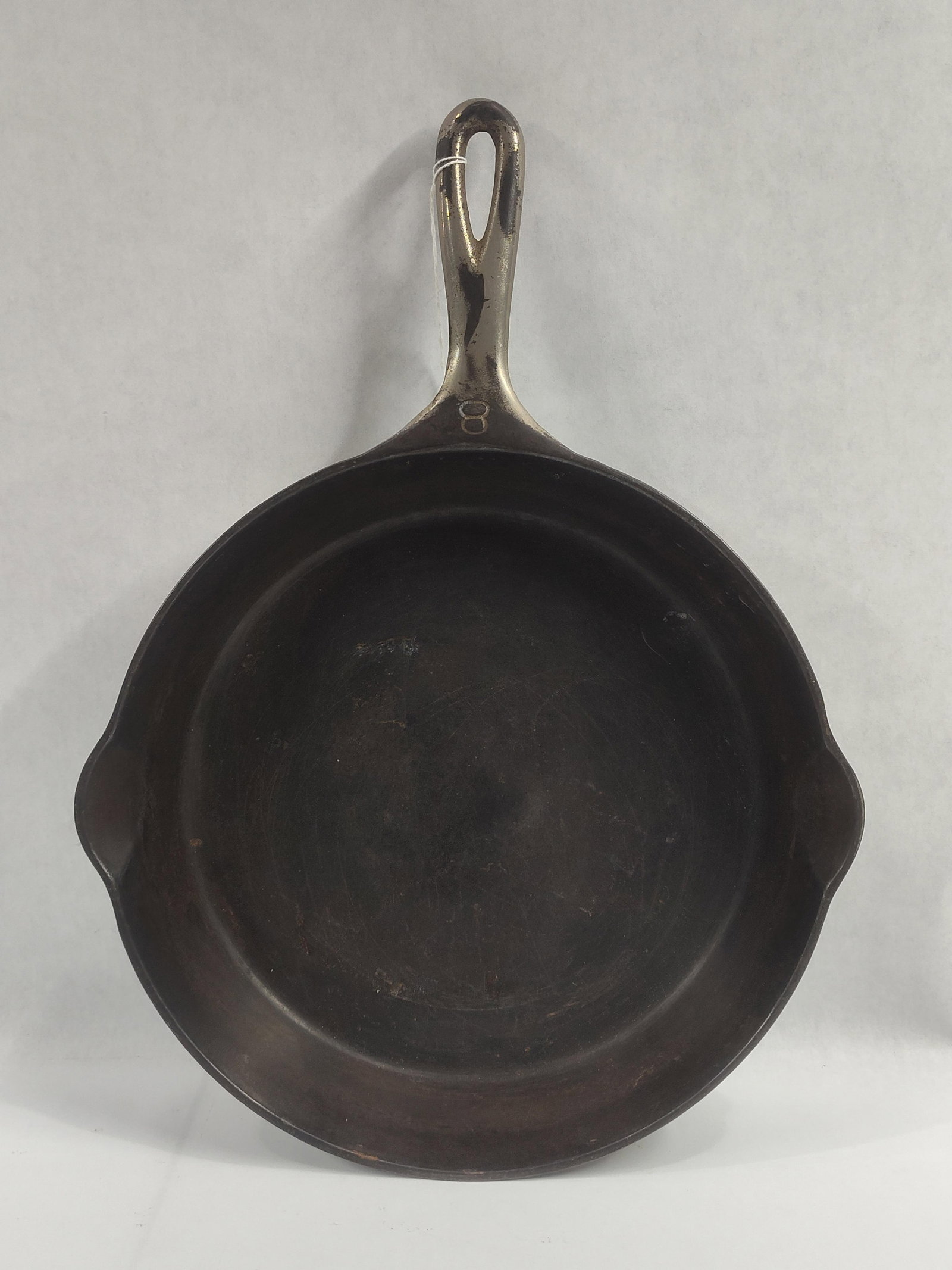 Griswold Number 8 Cast Iron Skillet with Small Logo Pattern 704: This cast iron skillet, size number 8, was manufactured by the Griswold Manufacturing Company of Erie, Pennsylvania. The skillet features a circular body with two integrated pour spouts and a handle w