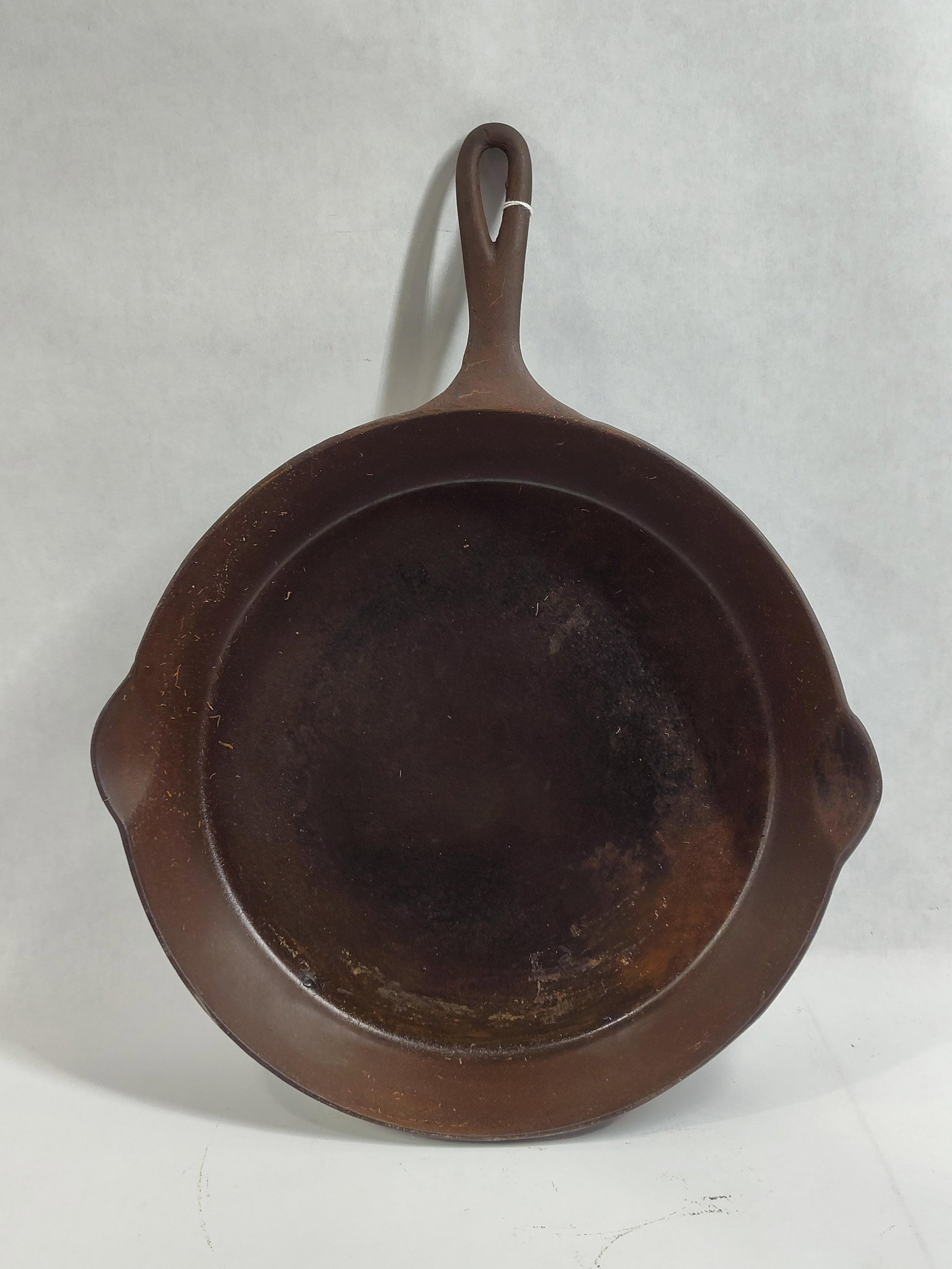 Wapak No. 10 Cast Iron Skillet with Erie Ghost Mark: This antique No. 10 cast iron skillet was manufactured by the Wapak Hollow Ware Company of Wapakoneta, Ohio. The piece is sand-cast with two integrated pour spouts and a handle featuring a teardrop-sh