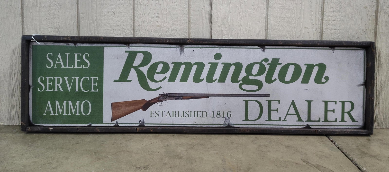 Remington Dealer Framed Advertising Sign: This is a framed advertising sign for Remington, produced as a modern decorative item in the style of adealer placard. The item consists of a printed panel housed in a dark-stained wooden frame. The g