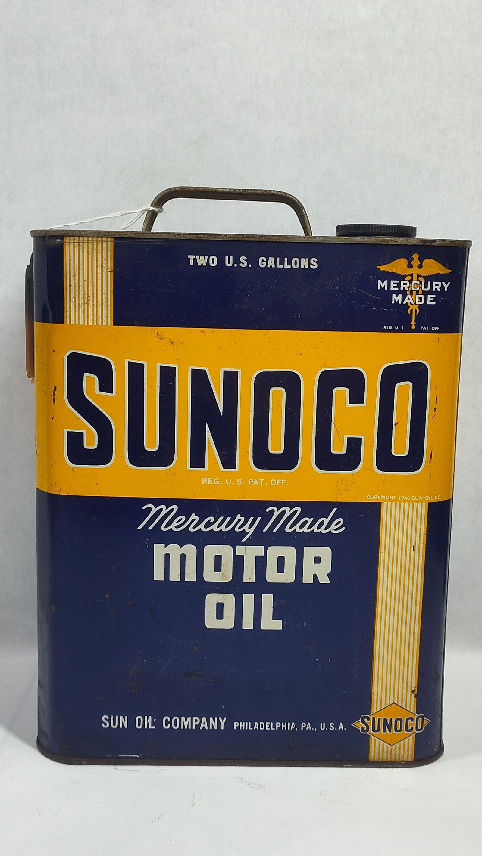 1946 Sunoco Mercury Made Two Gallon Motor Oil Can: This is atwo-gallon motor oil can produced for the Sun Oil Company, featuring a printed copyright date of 1946 on the front lower right. The rectangular container is constructed of lithographed tin an