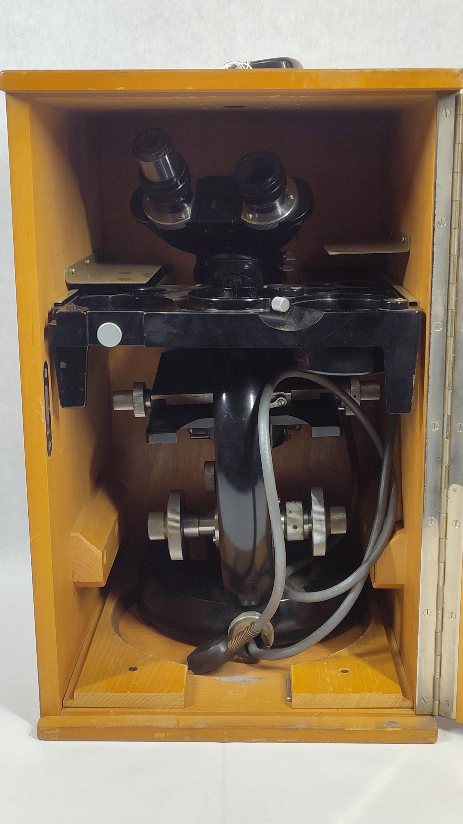 Binocular Laboratory Microscope Attributed to Carl Zeiss Jena in Fitted Wooden Case: Aprofessional-grade binocular laboratory microscope, attributed to Carl Zeiss Jena. The instrument features a heavy cast metal stand with a black enamel finish and bright-finished adjustment hardware.