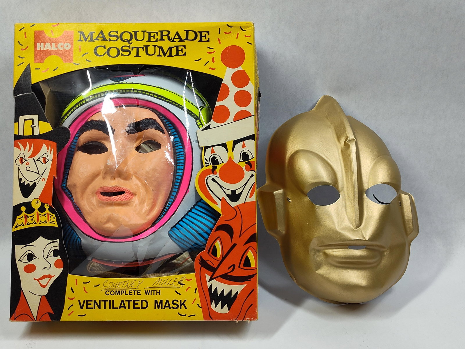 TwoHalloween Masks and Costume Including Halco Boxed Set: This lot features aHalco masquerade costume set in its original packaging and one additional loose mask. The boxed set includes a vacuum-formed plastic mask depicting a male face set within a colorful