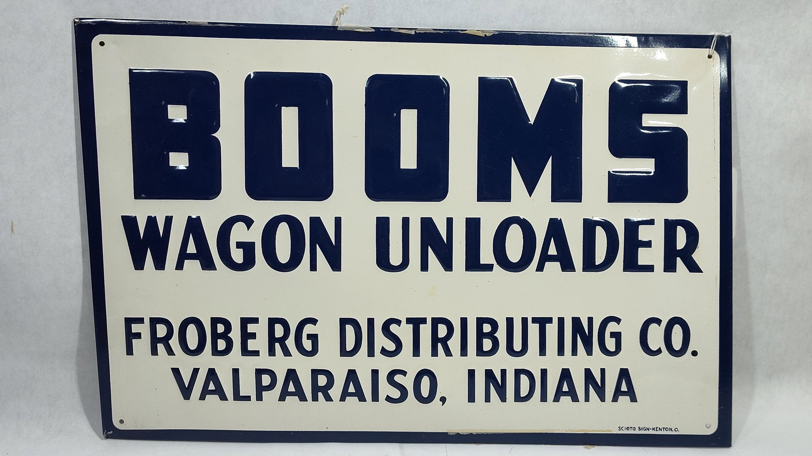 Embossed Metal Booms Wagon Unloader Advertising Sign, Scioto Sign Co.: This embossed metal advertising sign features promotional graphics for Booms Wagon Unloader, distributed by Froberg Distributing Co. of Valparaiso, Indiana. The sign was manufactured by the Scioto Sig