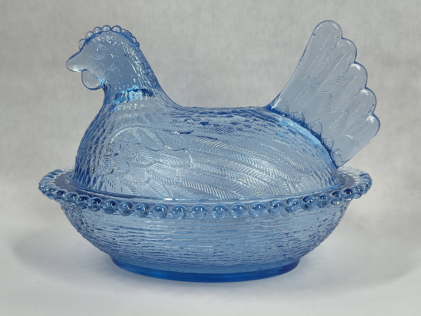 Indiana Glass Style Horizon Blue Translucent Pressed Glass Hen on a Nest Covered Dish: This two-piece covered dish is attributed to Indiana Glass and is modeled in the form of a hen on a nest. It is crafted from translucent pressed glass in a color often referred to as Horizon Blue or C