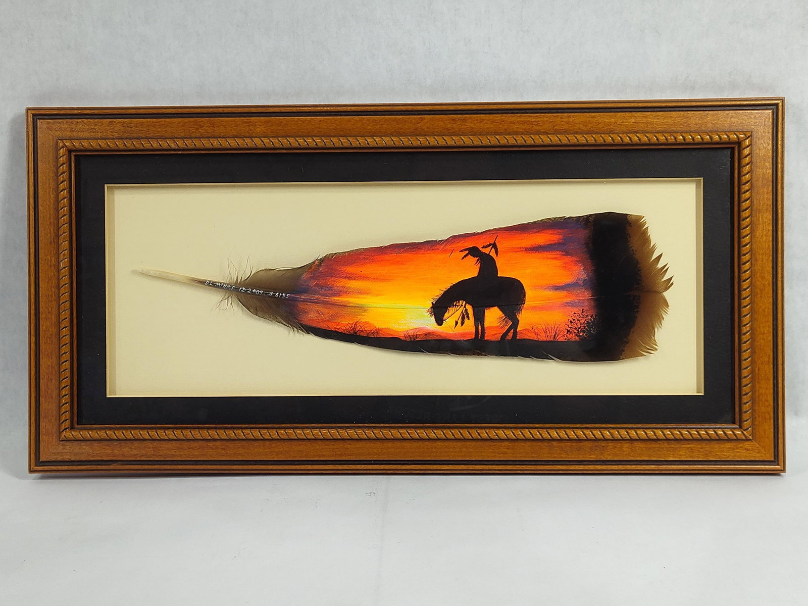 DL Miller, Hand-Painted Feather Art, Native American on Horseback at Sunset, 2004: A contemporary mixed-media painting by artist DL Miller, executed on a natural feather support, likely a turkey feather. The artwork features a silhouette of a Native American figure on horseback in a