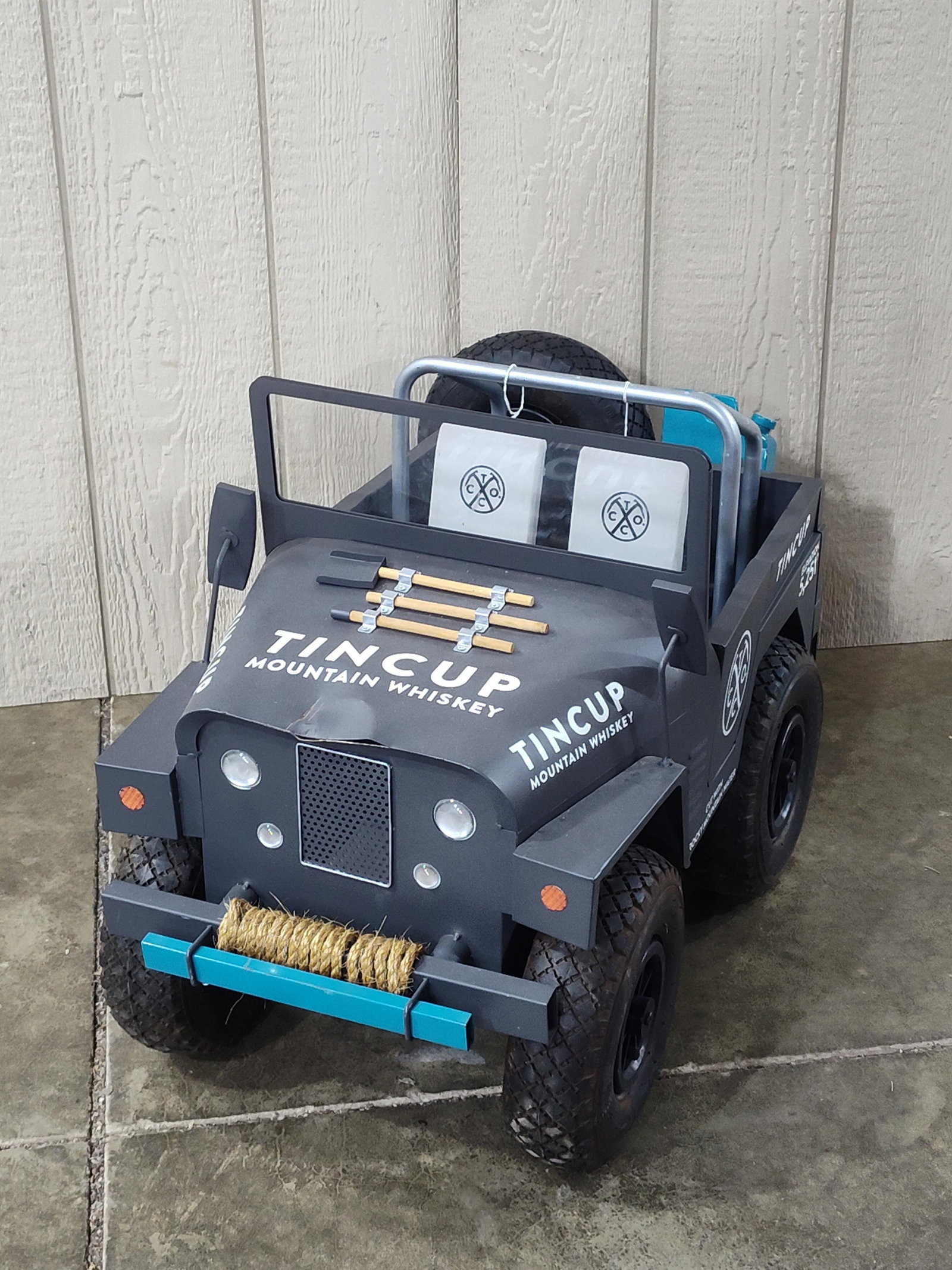 Tincup Mountain Whiskey Custom Metal Promotional Jeep Display: A large-scale promotional display piece modeled after amilitary jeep, custom-fabricated for Tincup Mountain Whiskey. The construction consists of a heavy-gauge sheet metal body with welded seams