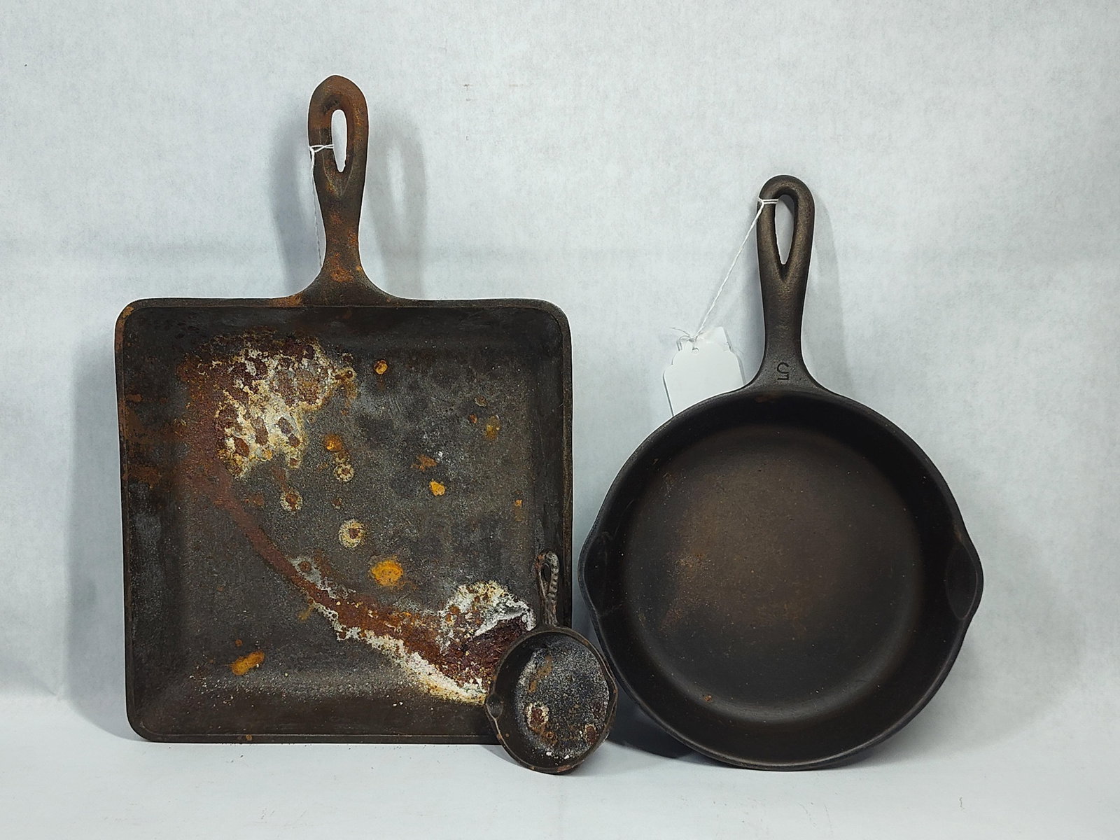 A Trio ofCast Iron Skillets Including Wagner Ware: This lot consists of threecast iron skillets. The first is a round skillet featuring two pour spouts and a handle marked with the number 5. The base contains the stylized Wagner Ware Sidney -O- logo