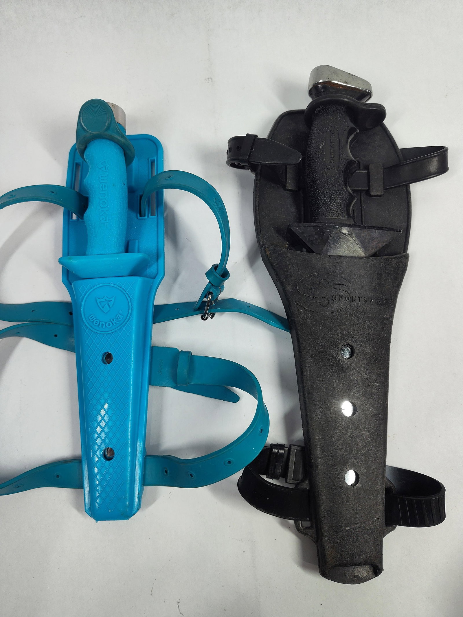 TwoDiving Knives Including Wenoka and Scubapro Models: This lot includes twofixed-blade diving knives, complete with their respective sheaths and leg straps. The first knife is a Wenoka brand model, featuring a blue molded textured plastic handle with fin