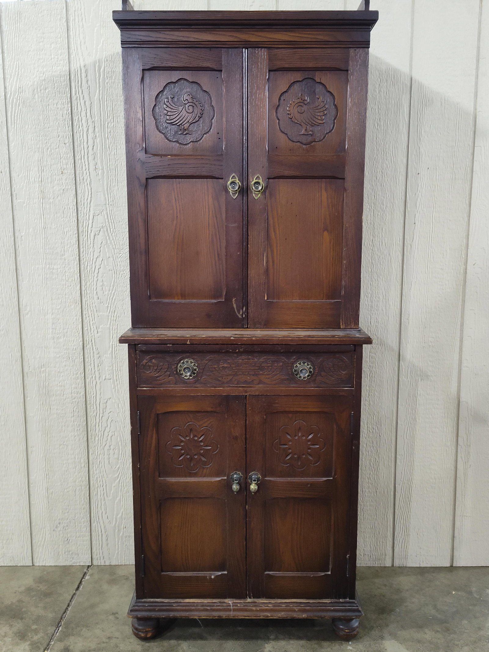 Two-Piece Carved Oak Spanish Colonial Revival Style Bar Cabinet: A two-piece bar or liquor cabinet constructed from dark-stained oak in the Spanish Colonial Revival style. The upper section features a decorative scalloped top gallery and two cabinet doors, each acc