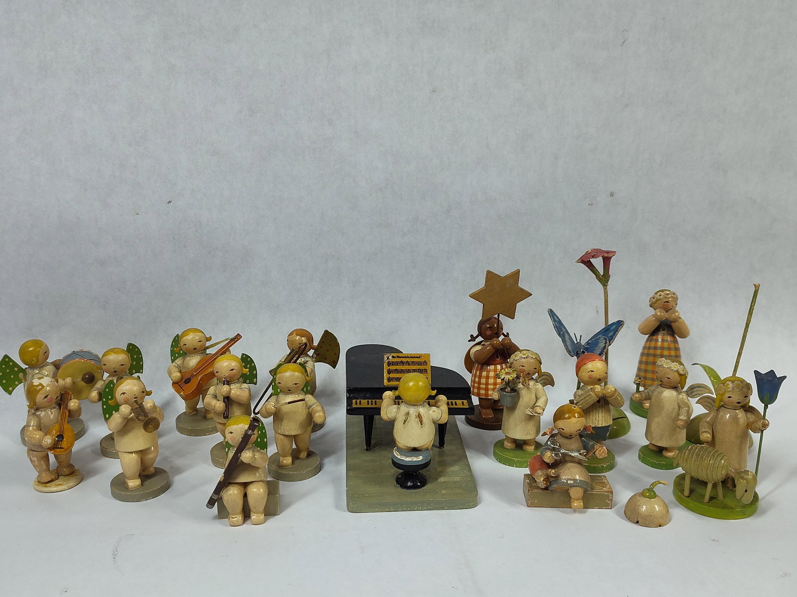 Collection of Wendt and Kuhn Hand-Painted Wooden Figurines: hand-painted wooden figurines manufactured by Wendt and Kuhn of Grunhainichen, Germany. The assembly primarily features an angel orchestra, characterized by the maker signature green wings decorated w