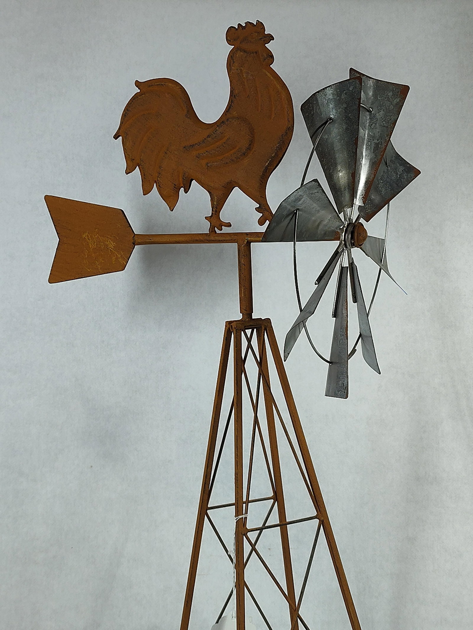 Decorative Iron Rooster Windmill Garden Stand: A contemporary decorative garden windmill stand in the rustic farmhouse style, resembling designs by manufacturers such as Zaer Ltd. The piece is crafted from iron and features a tall tripod base with