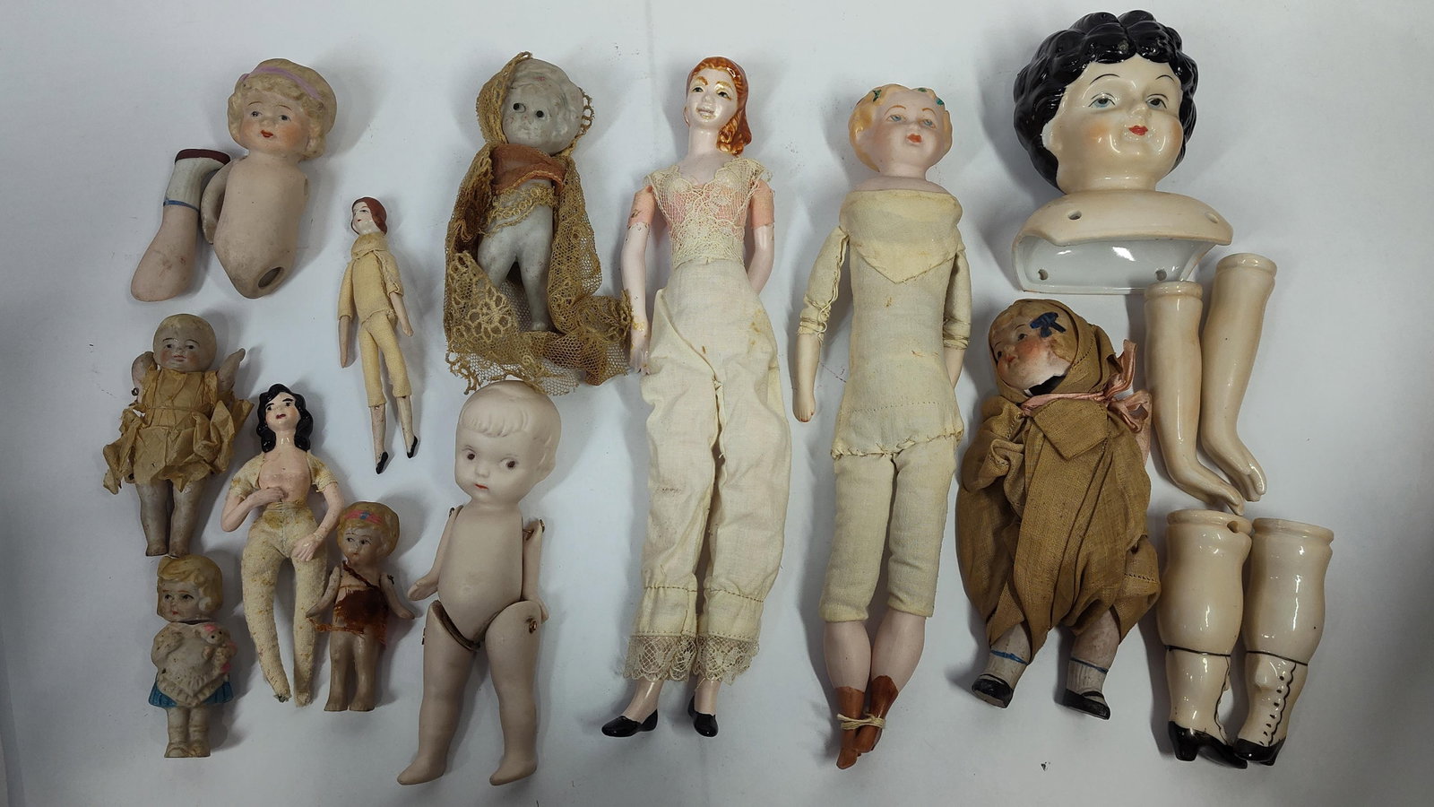 An Assortment of Antique Bisque and China Dolls and Replacement Parts: An assortment of antique dolls and component parts, primarily executed in bisque and glazed porcelain, consistent with late 19th and early 20th-century European production. The group includes a large 